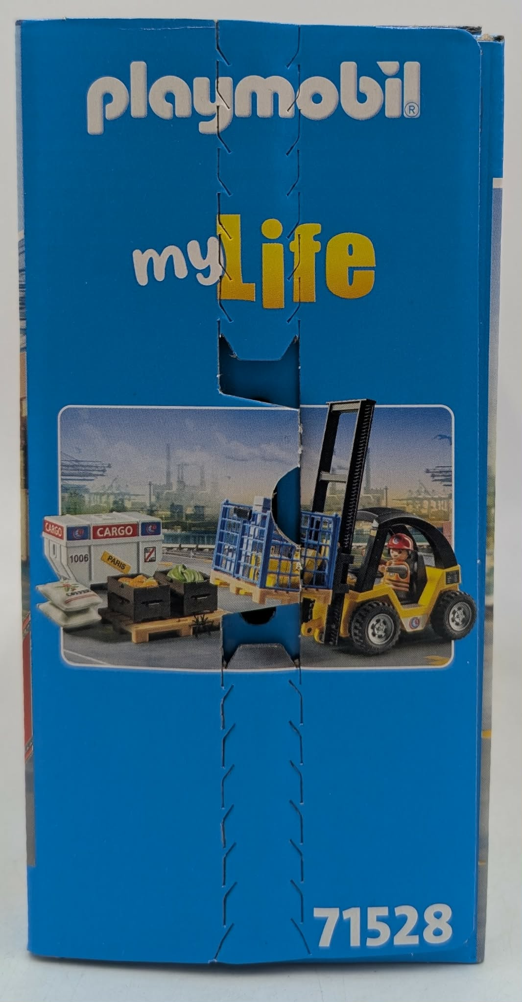 Carrello elevatore giallo con conducente carica casse blu su un pallet. Porto sullo sfondo.