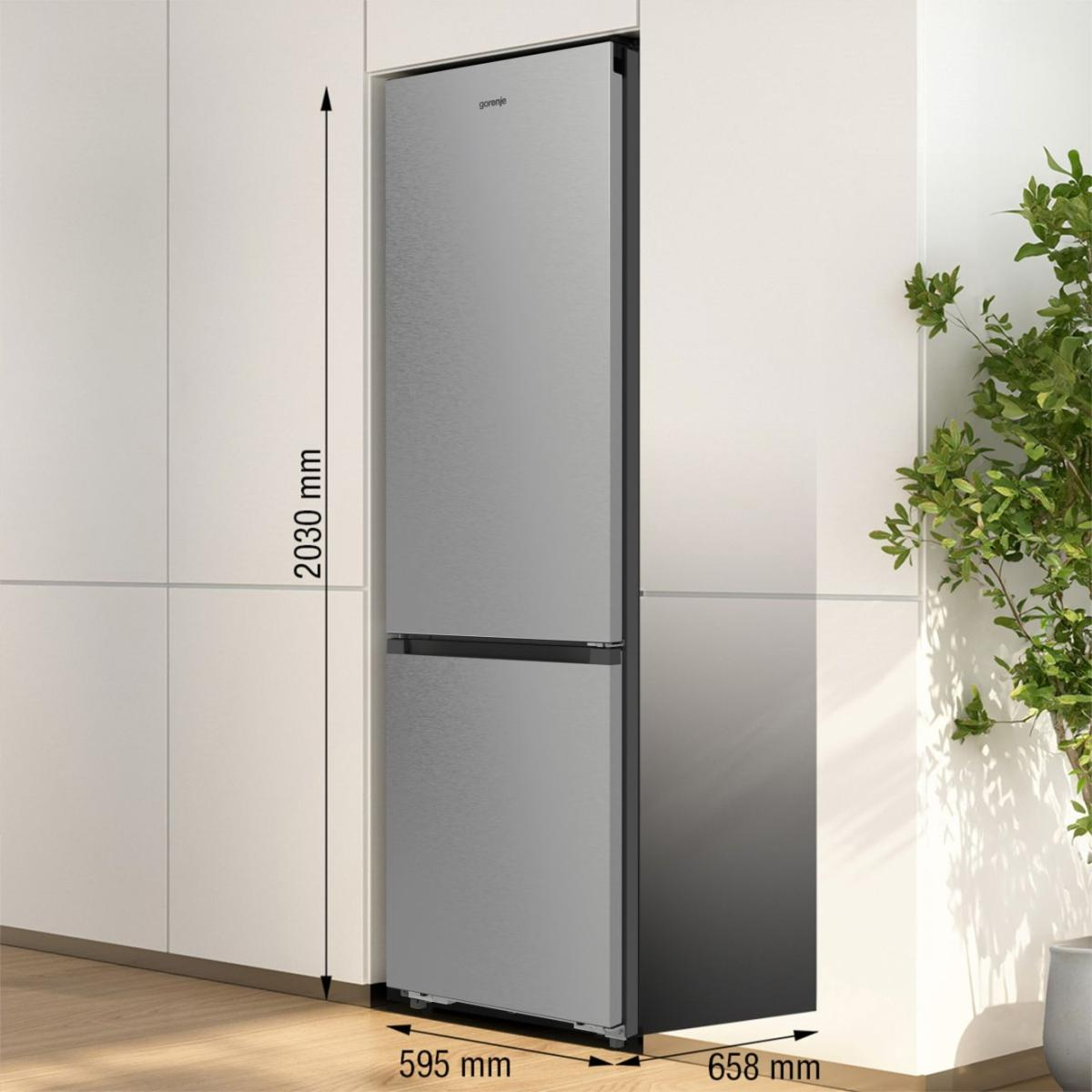 Ein silberner Gorenje-Kühlschrank mit zwei Türen steht neben weißen Küchenschränken.
