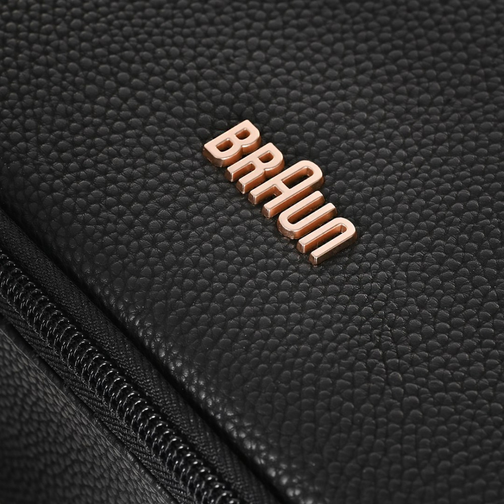 Zbliżenie czarnej skórzanej torby z srebrnym zamkiem błyskawicznym i miedzianym logo „Braun”.