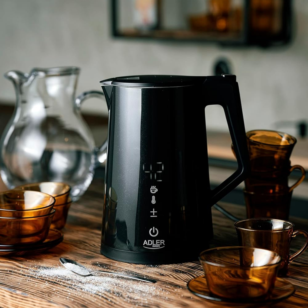 Ein schwarzer Wasserkocher mit digitaler Anzeige steht auf einem Holztisch neben Glaskaraffe und braunen Tassen.