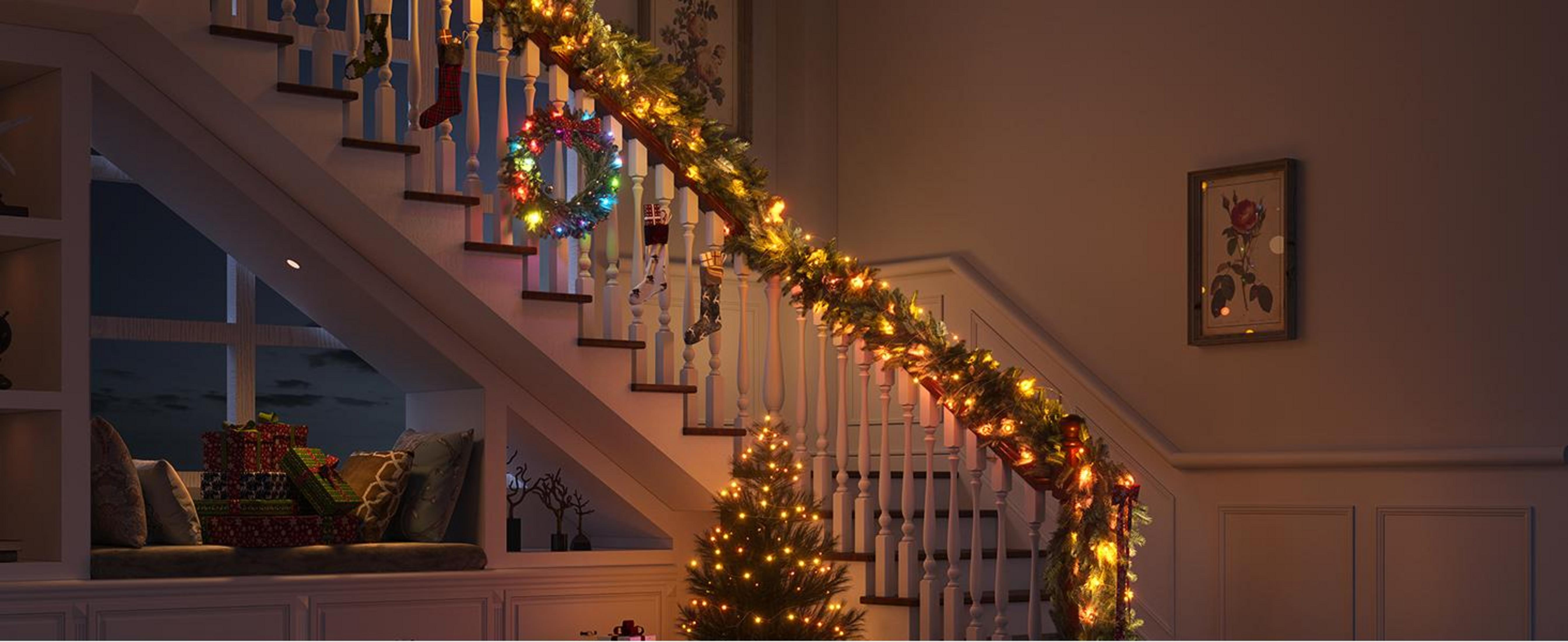 Beleuchtete Treppe mit Weihnachtsgirlande, Lichtern, Socken und Geschenken.