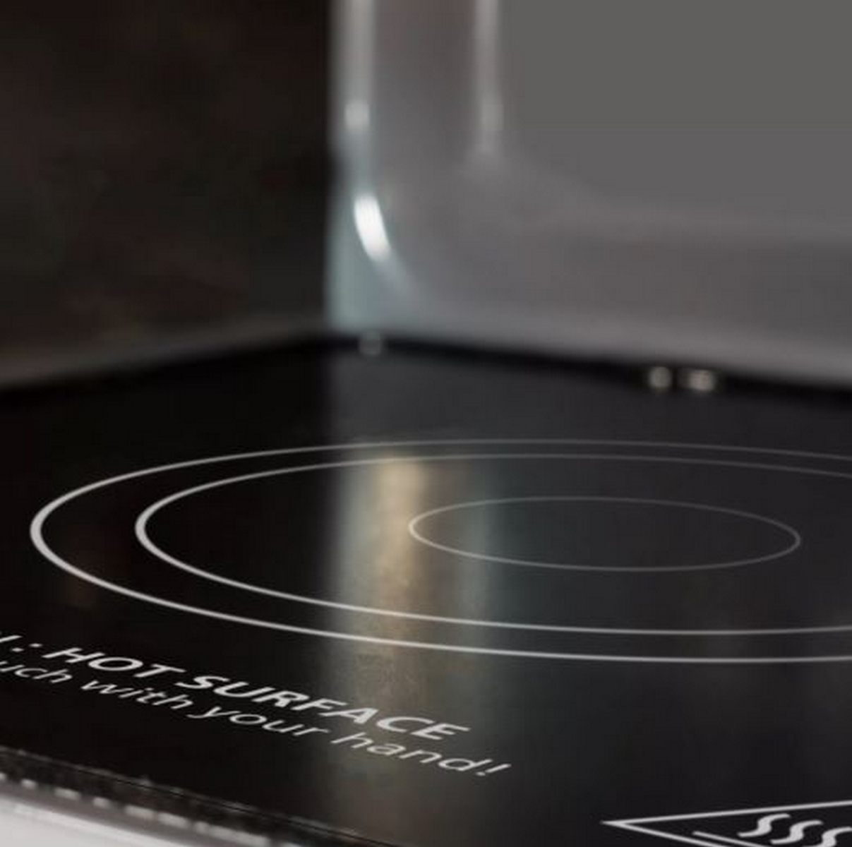 Placa de cocina negra con espirales de calentamiento blancas y advertencia.