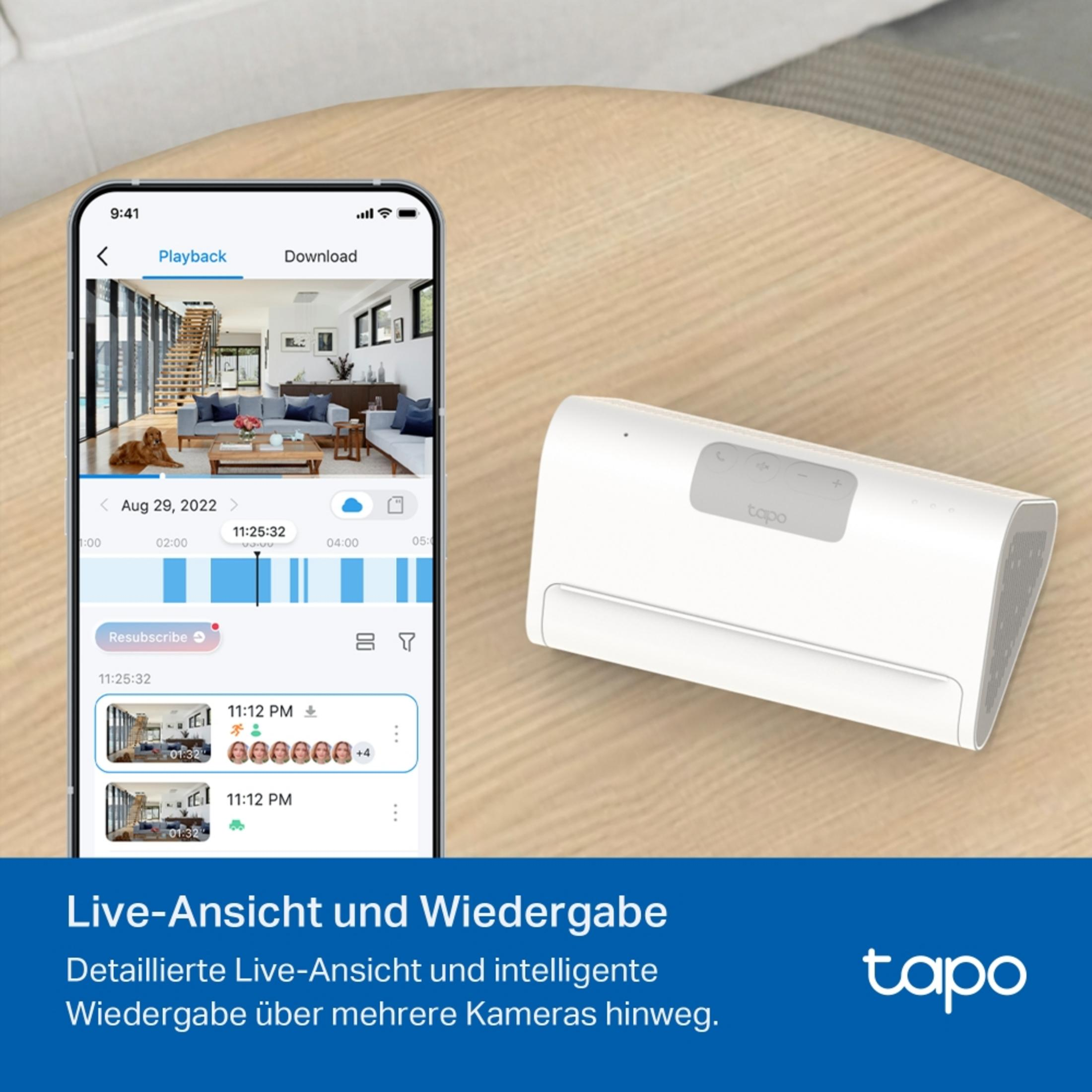 Ein Smartphone zeigt eine Überwachungskamera-App neben einem weißen Tapo-Gerät auf einem Holztisch.