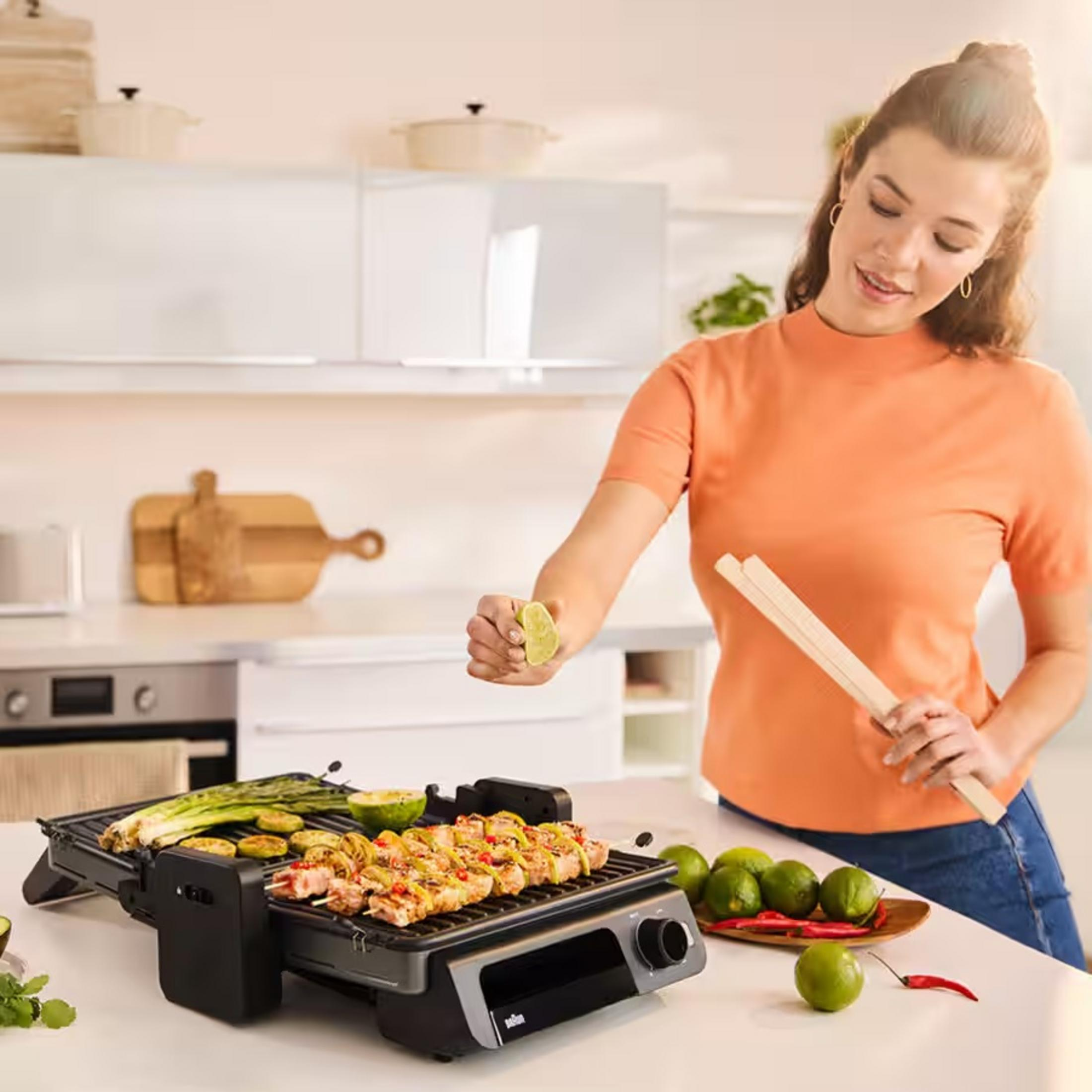 Frau presst Limette über Grill mit Spießen, Gemüse und Kräutern.