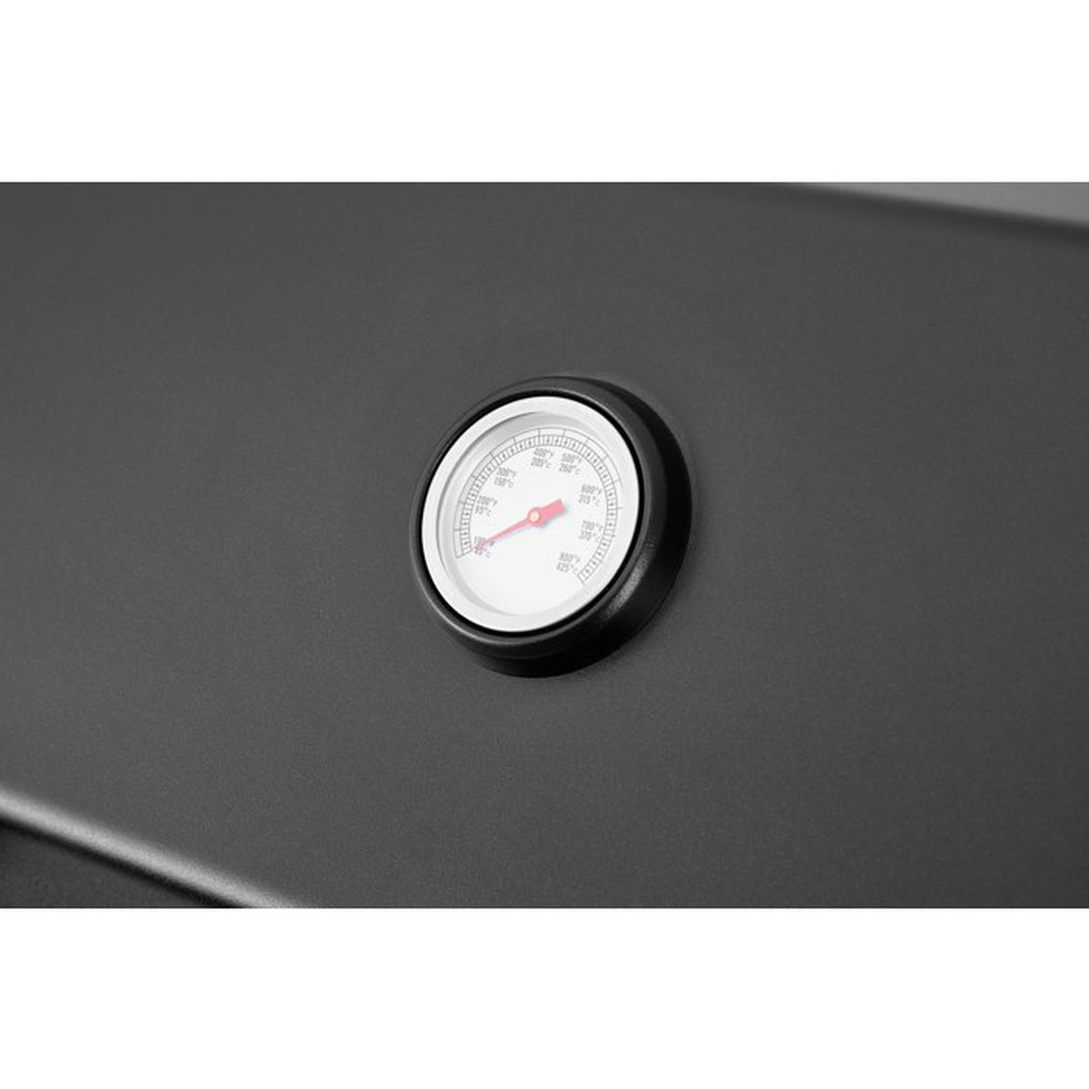 Ein Thermometer auf einer dunklen Oberfläche mit roten Zeigern.