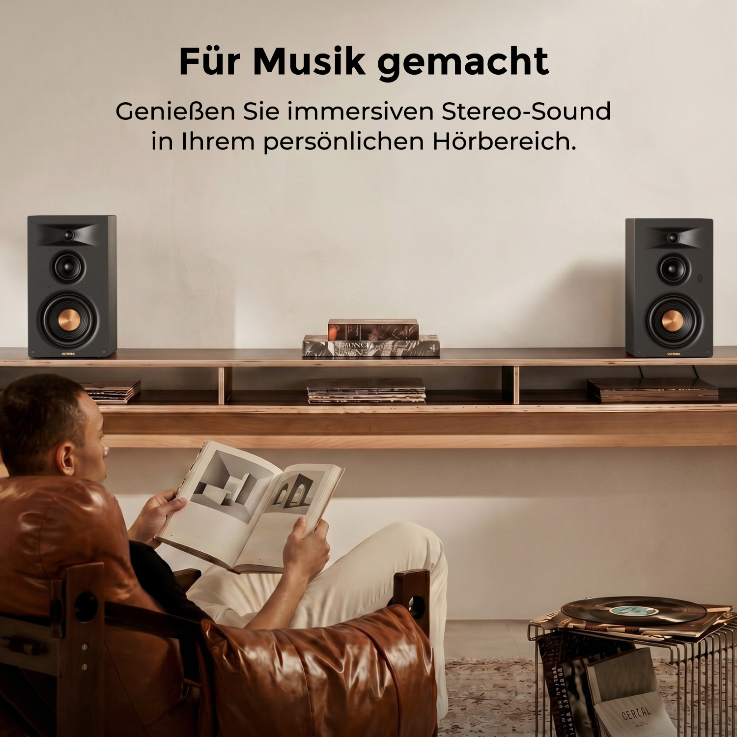 Mann liest Buch, zwei Lautsprecher auf Regal, Vinyls auf Tisch.