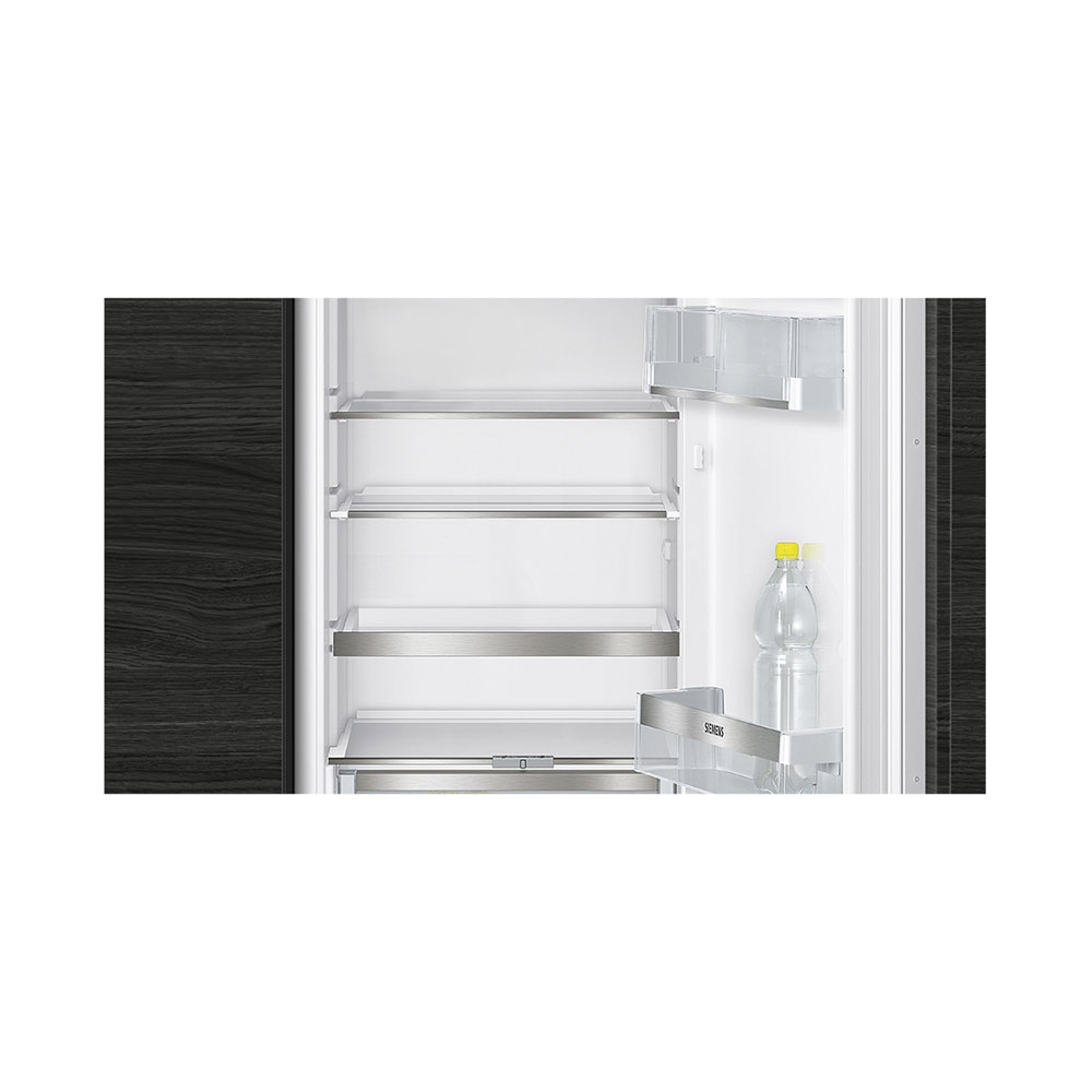 Ein leerer Kühlschrank mit Glasablagen und einer Wasserflasche.