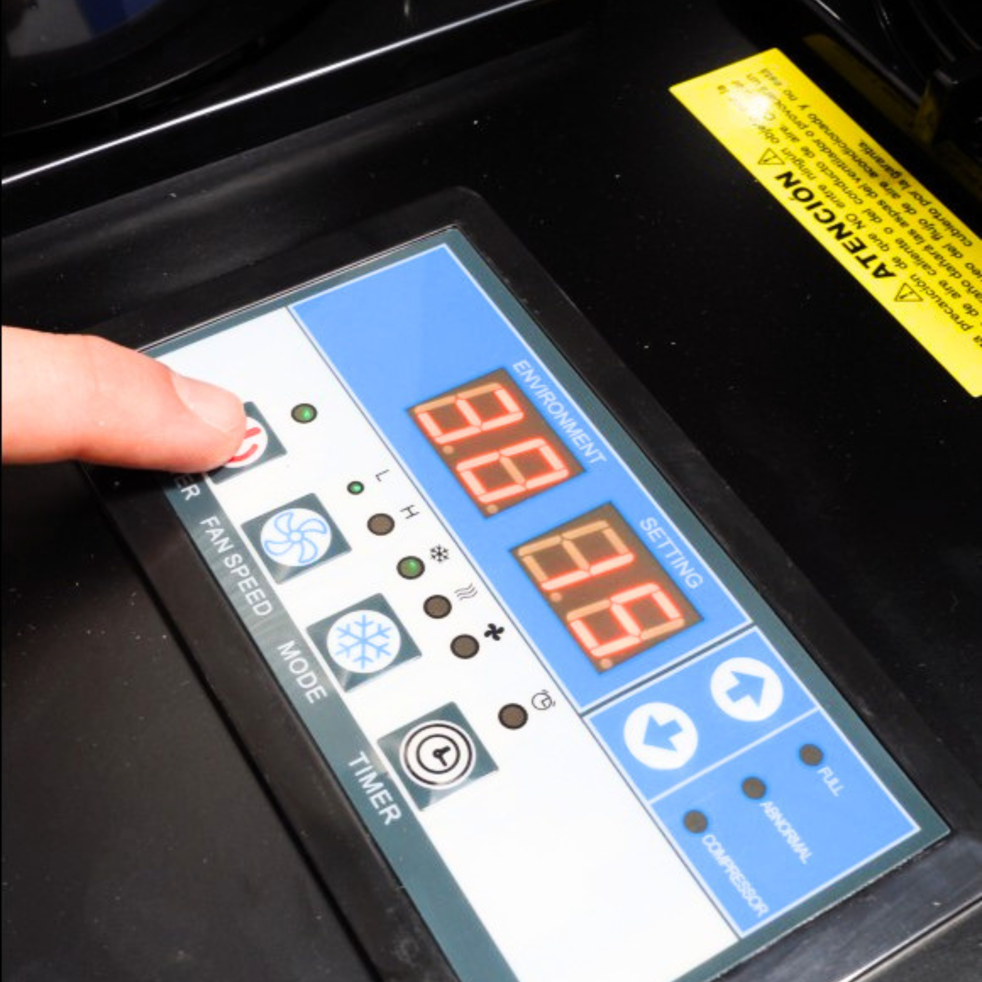 Un dedo presiona un botón en un panel de control con pantallas digitales.