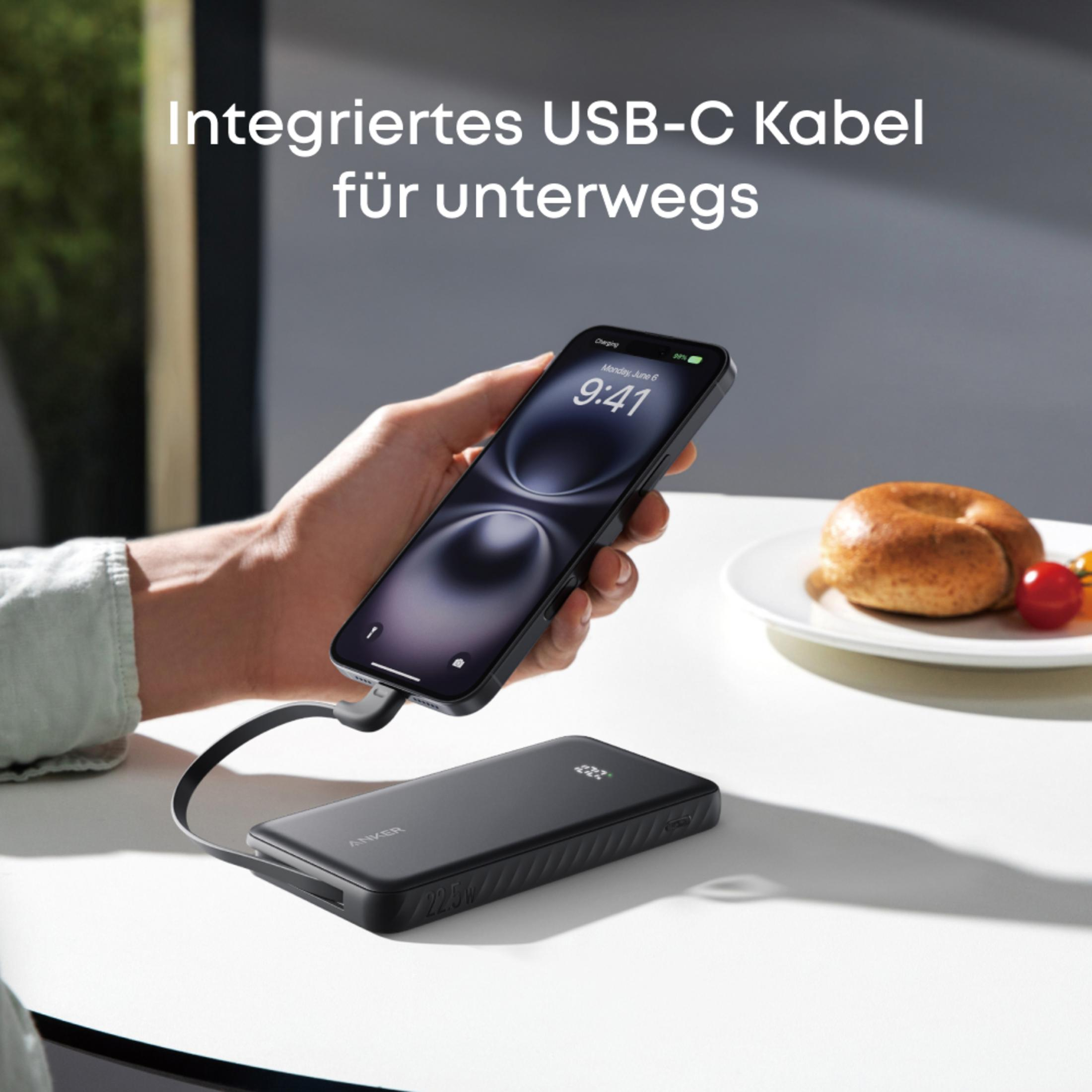 Eine Hand hält ein iPhone, das an eine schwarze Powerbank mit integriertem USB-C Kabel angeschlossen ist.