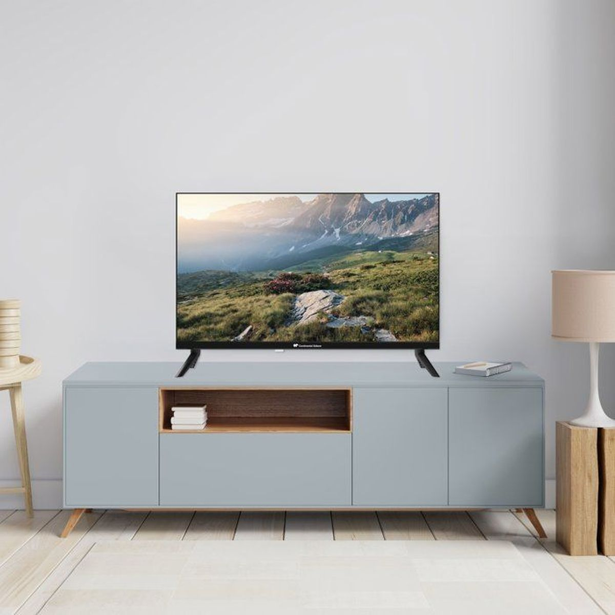 Una TV su un mobile grigio mostra un paesaggio montano. Un tavolino è nelle vicinanze.