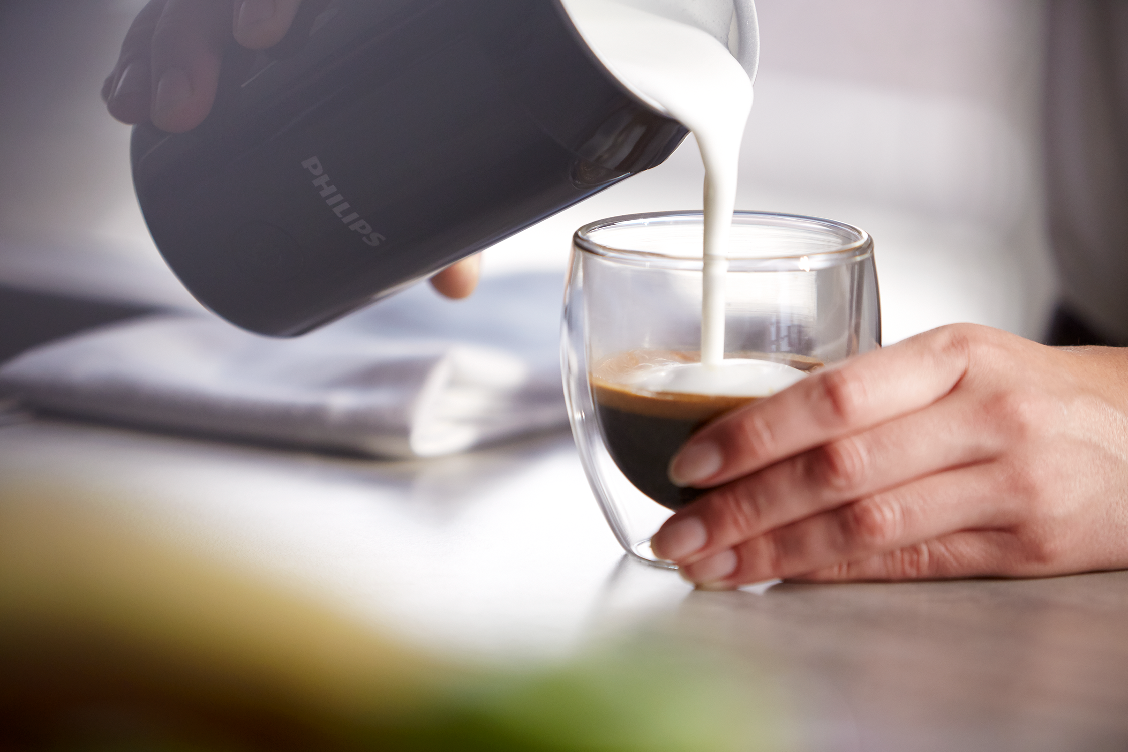 Mleko wlewane z dzbanka Philips do szklanki z espresso.