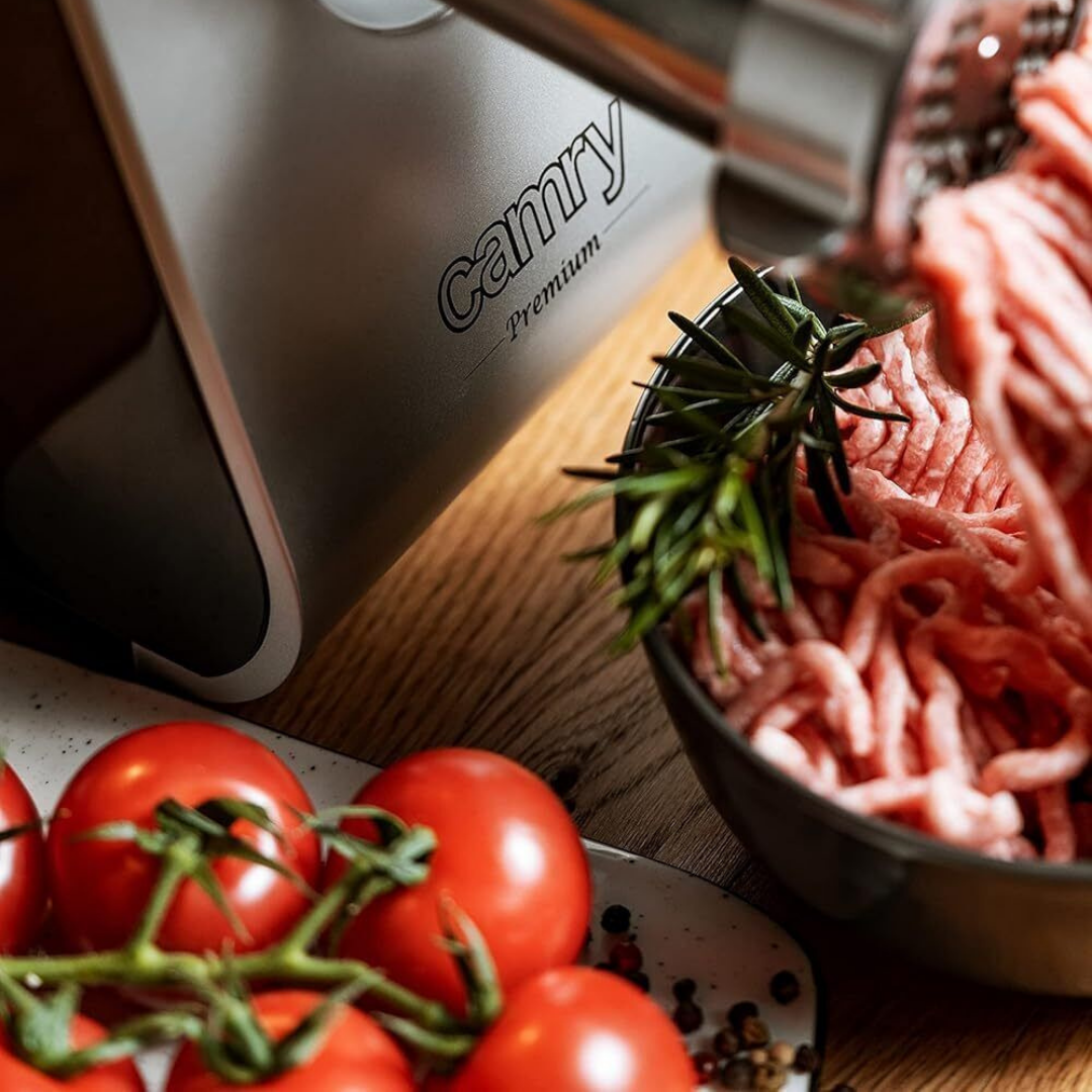 Fleischwolf mit Hackfleisch, Tomaten und Rosmarin auf Holztisch