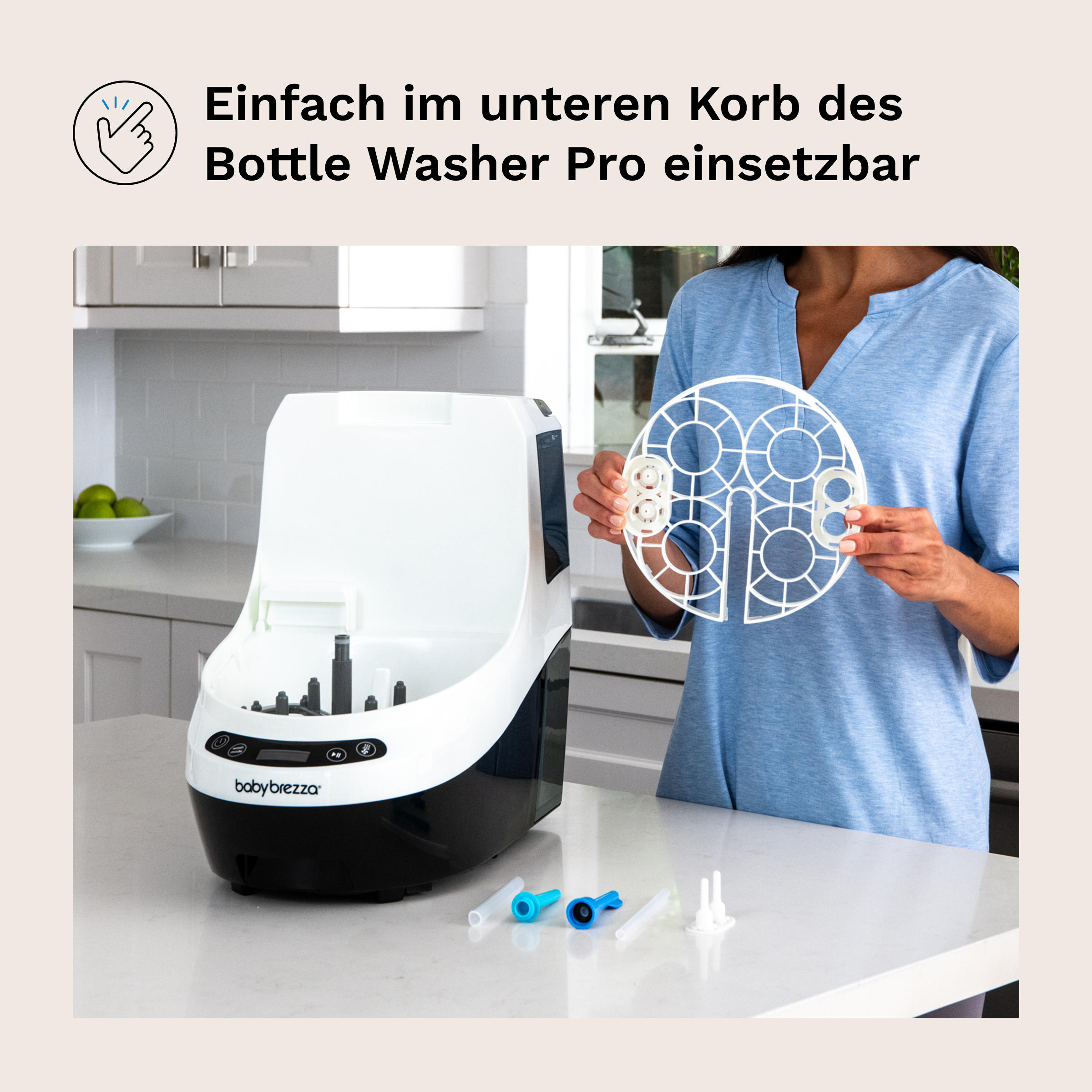 Baby Brezza Flaschenwascher mit Zubehör und Einsatz. Küche im Hintergrund.