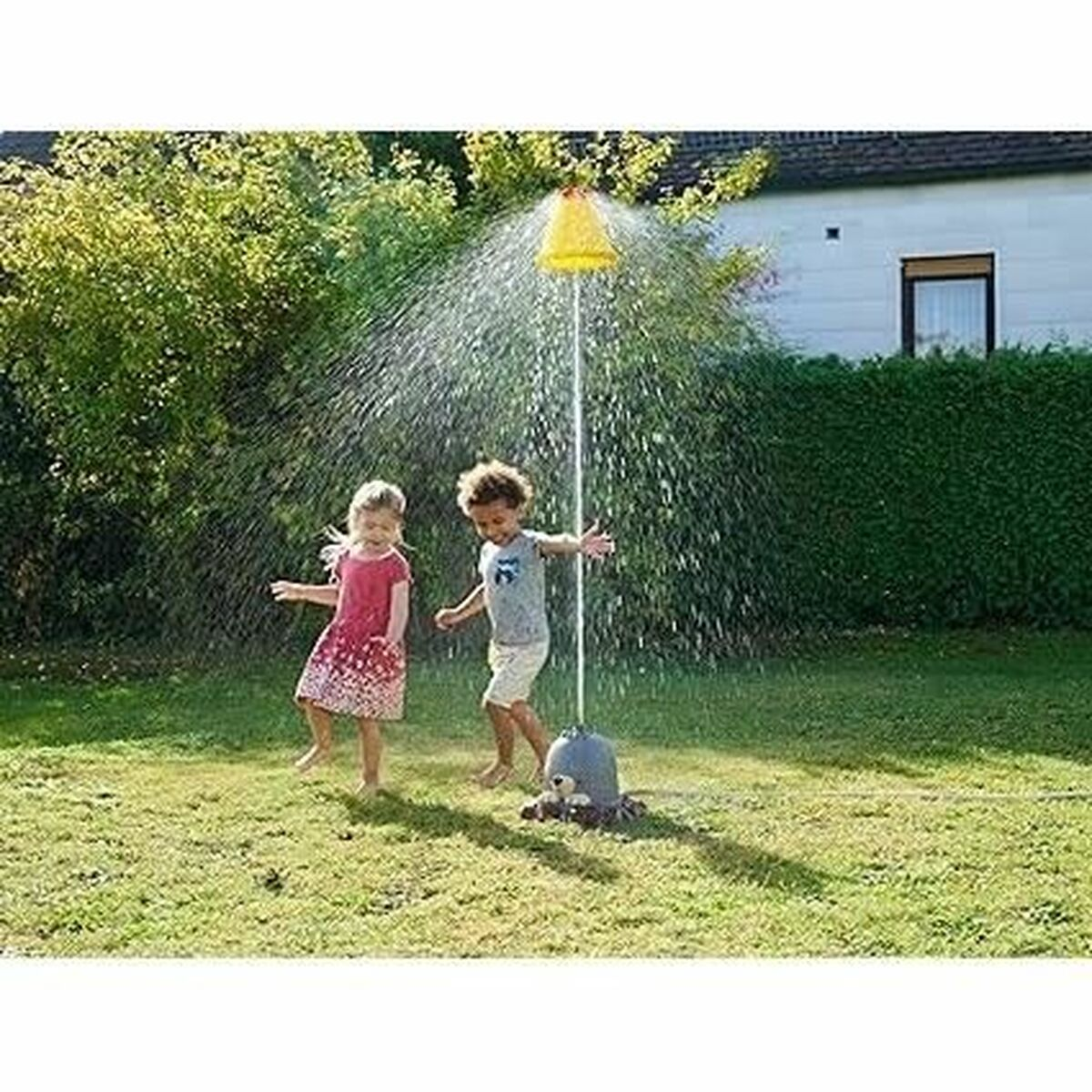 Zwei Kinder spielen im Rasen unter einem Wassersprinkler mit einem gelben Kegel.