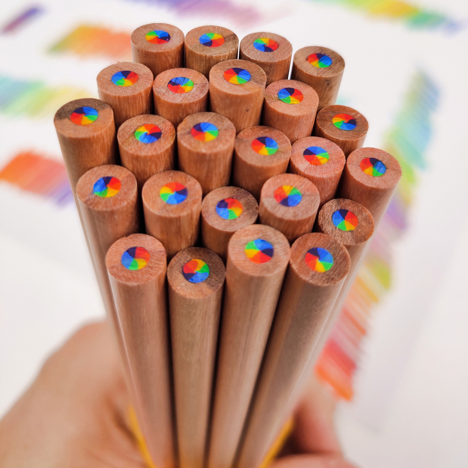 Mazzo di matite di legno con punte colorate, tenute da una mano.