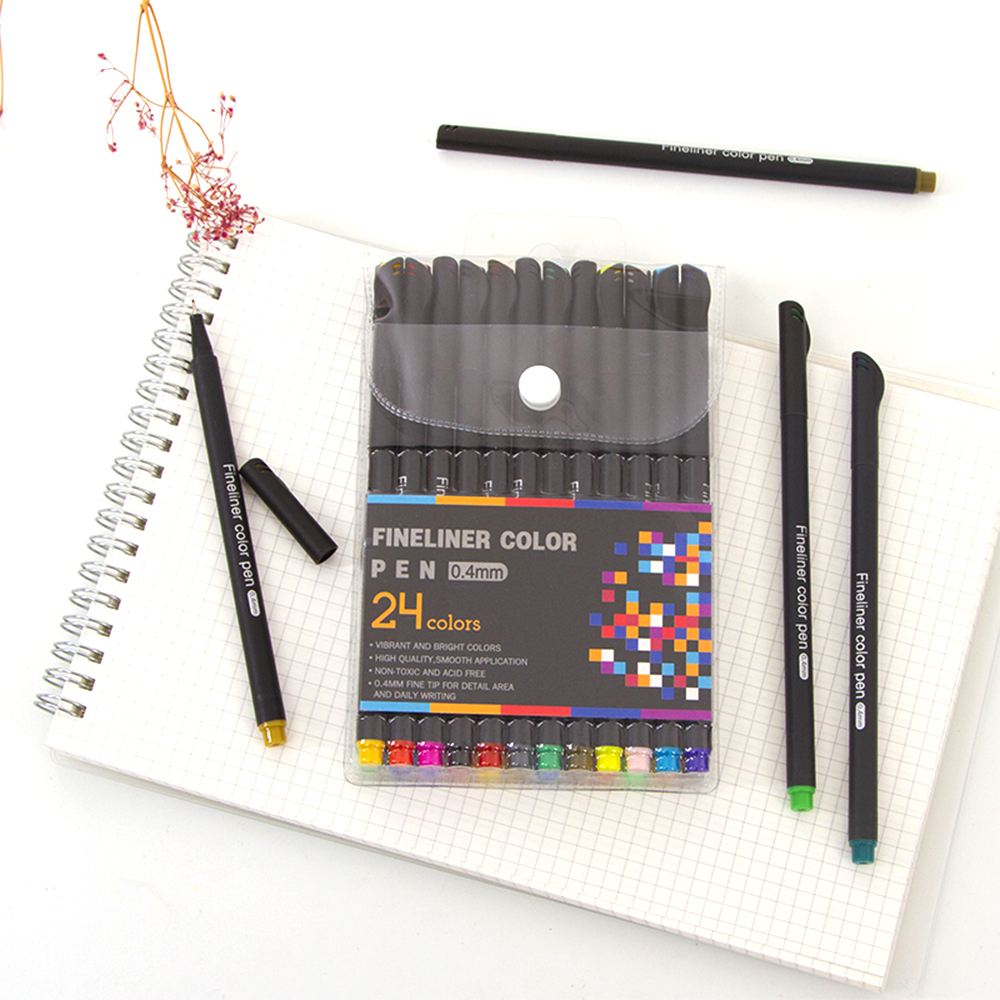 Un set di 24 penne fineliner in vari colori è esposto su un taccuino, con tre penne sfuse nelle vicinanze.