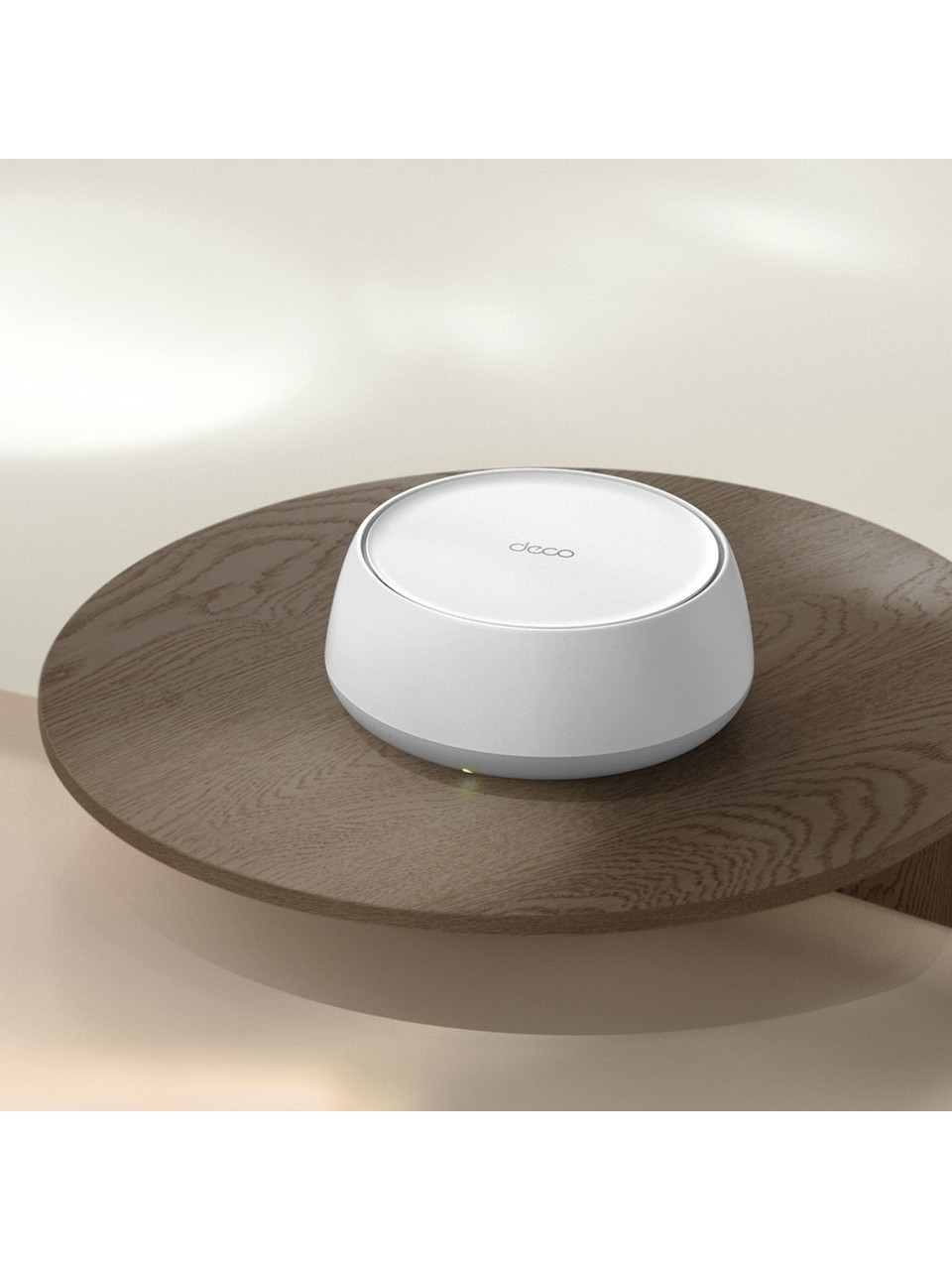 Biały router Deco stoi na okrągłym drewnianym stole z jasnobeżowym tłem.