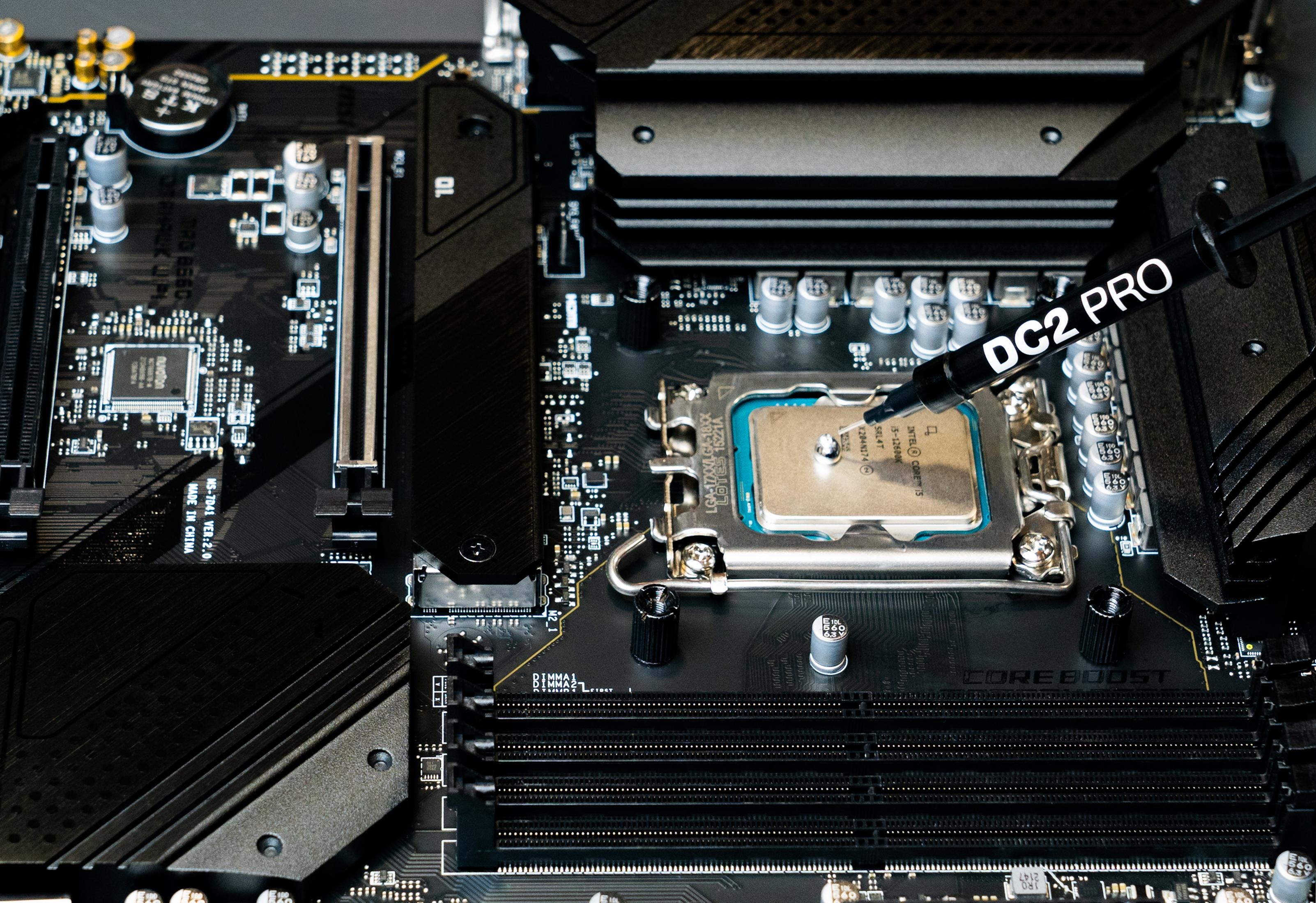 Eine Spritze mit Wärmeleitpaste auf einer Computerplatine über einer CPU.