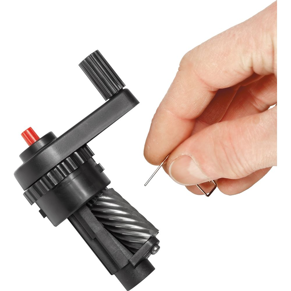 Hand hält Metallstift nahe schwarzem Spitzer mit Kurbel und rotem Knopf.