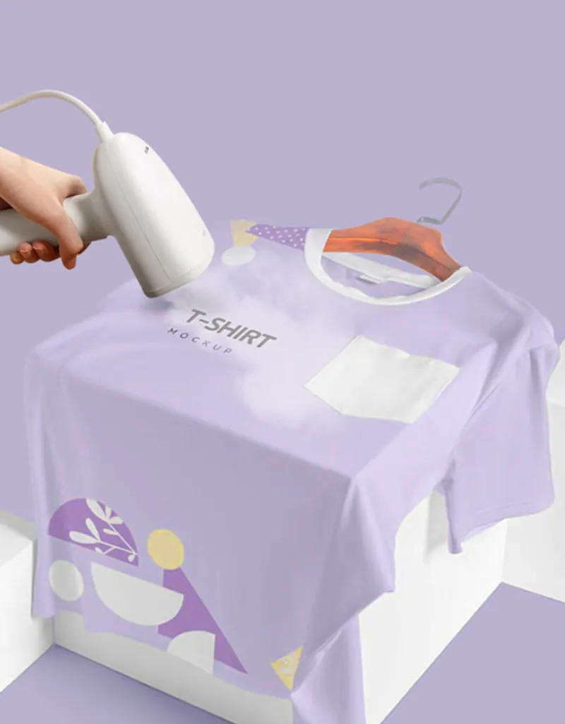 Hand bügelt ein lila T-Shirt mit Muster auf einem Kleiderbügel.