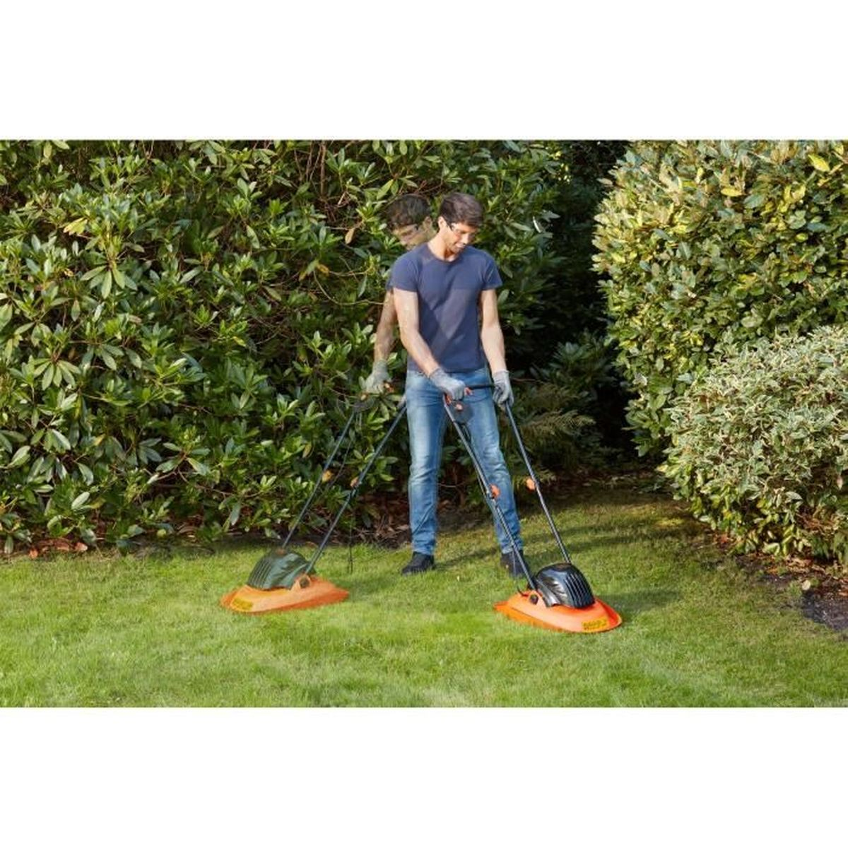 Ein Mann mäht den Rasen mit zwei Rasenmähern im Garten.