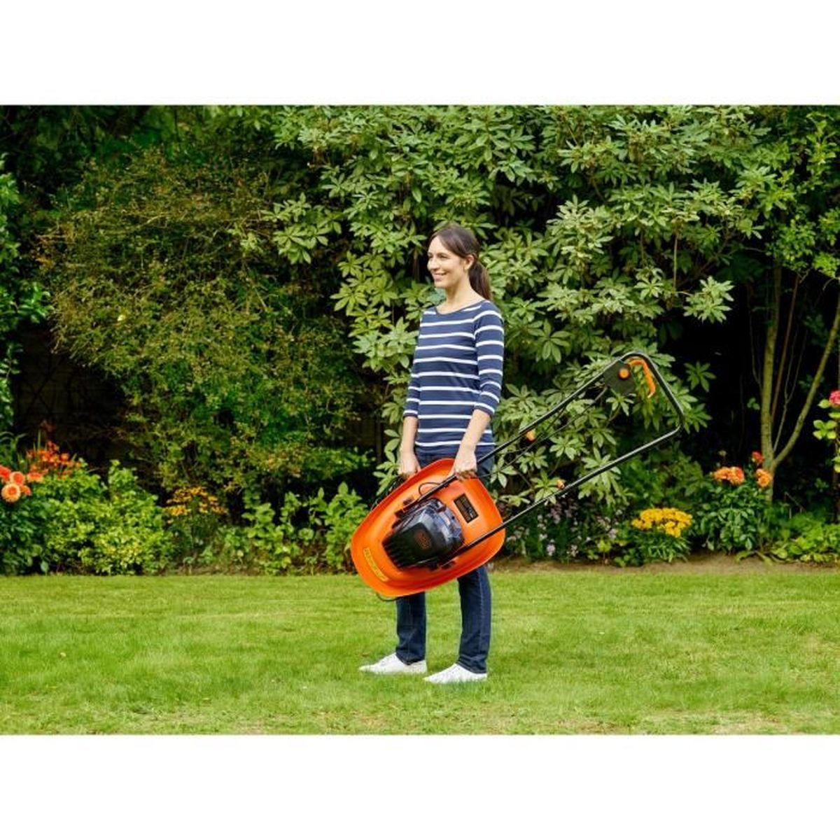 Frau mit einem orangefarbenen Rasenmäher im Garten auf grünem Gras.