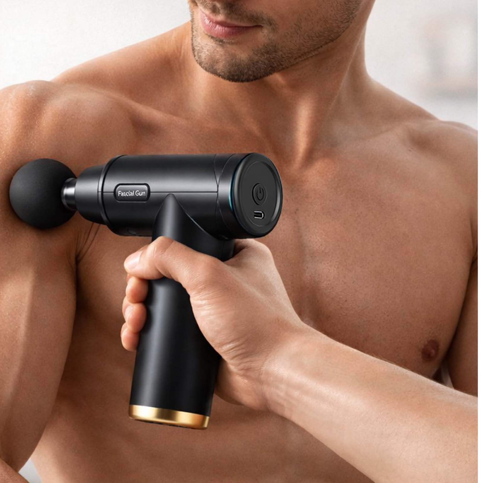 Mann benutzt eine schwarze Massagepistole auf seiner Schulter. Goldene Akzente am Griff.