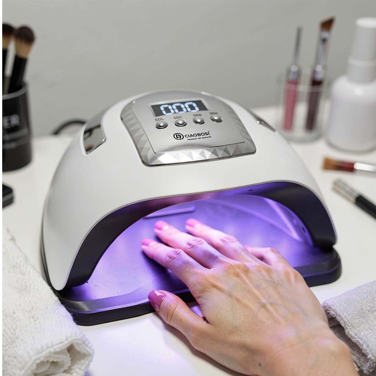 Eine Hand mit pinkem Nagellack wird unter einer UV-Nagellampe getrocknet.