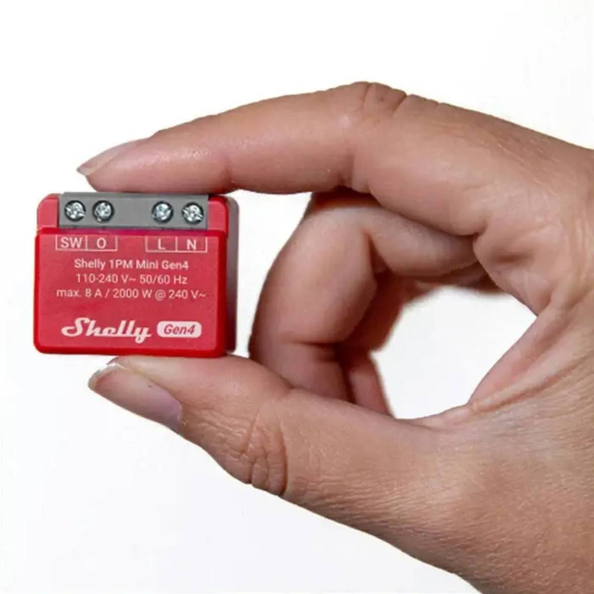 Etiketli küçük kırmızı bir Shelly 1PM Mini Gen4 cihazı tutan el.