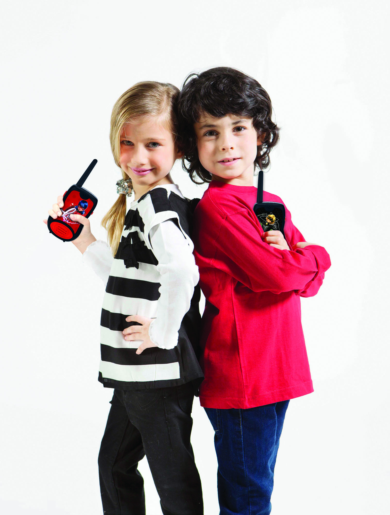 Due bambini schiena contro schiena tengono walkie-talkie. Bambina a sinistra, bambino a destra.
