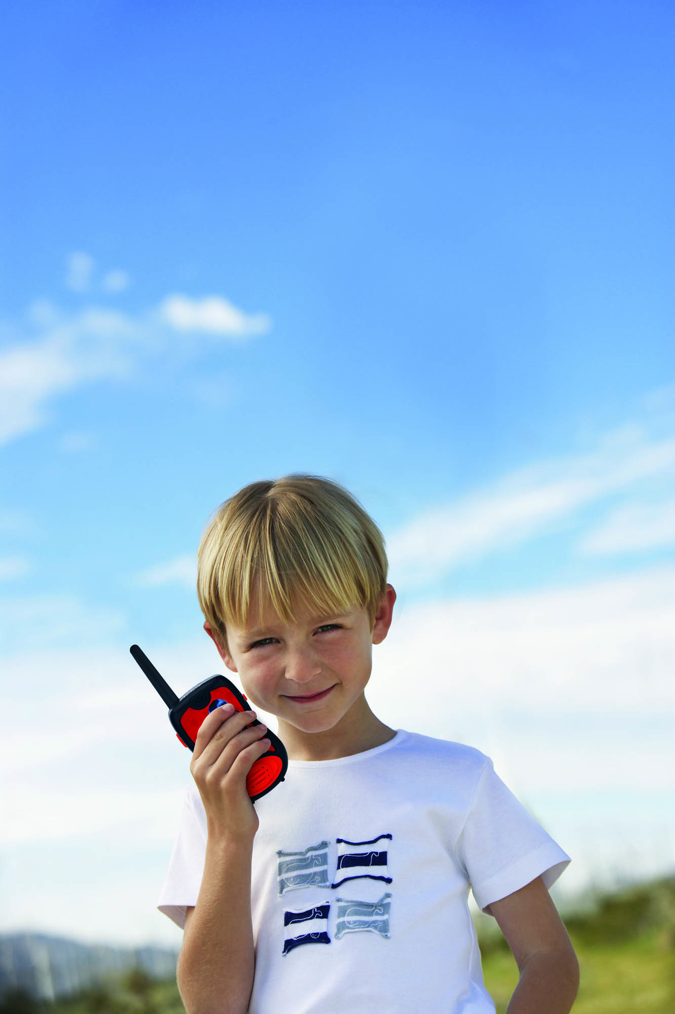 Un ragazzo biondo tiene in mano un walkie-talkie rosso e nero.