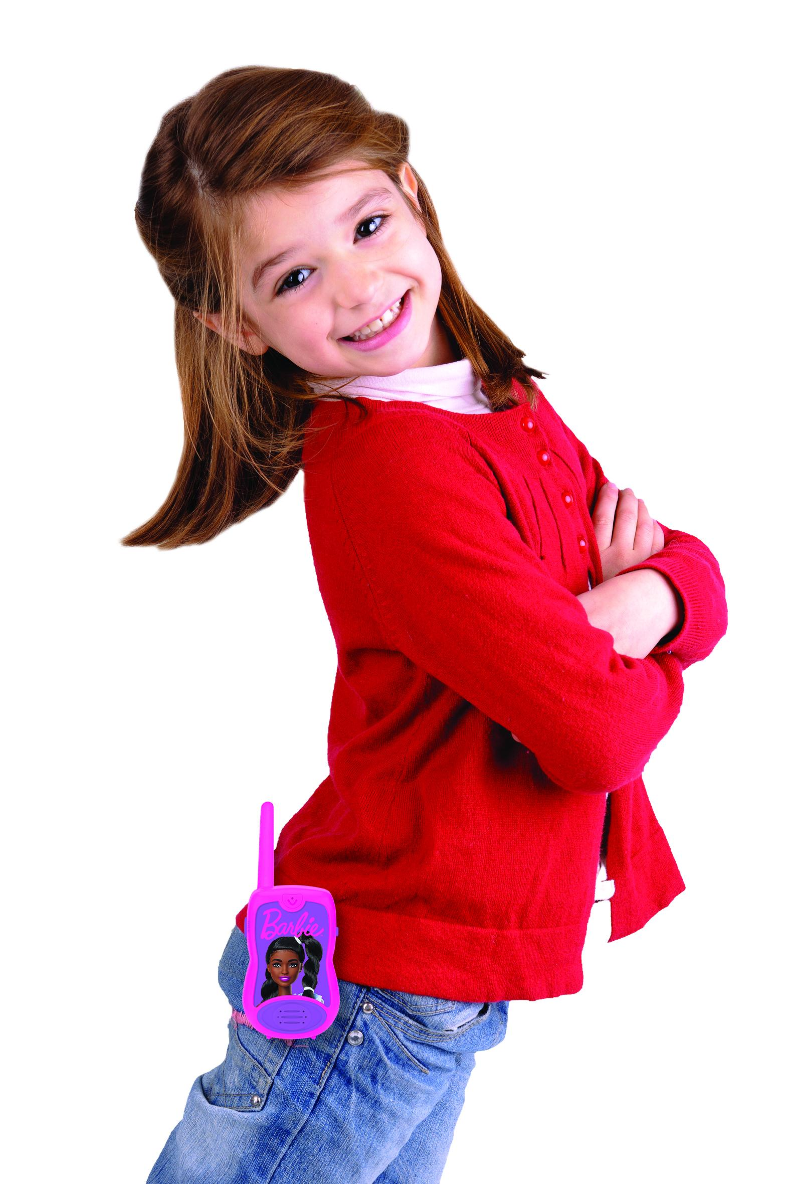 Una bambina con capelli castani indossa un cardigan rosso e jeans. Un walkie-talkie rosa Barbie è agganciato ai suoi pantaloni.