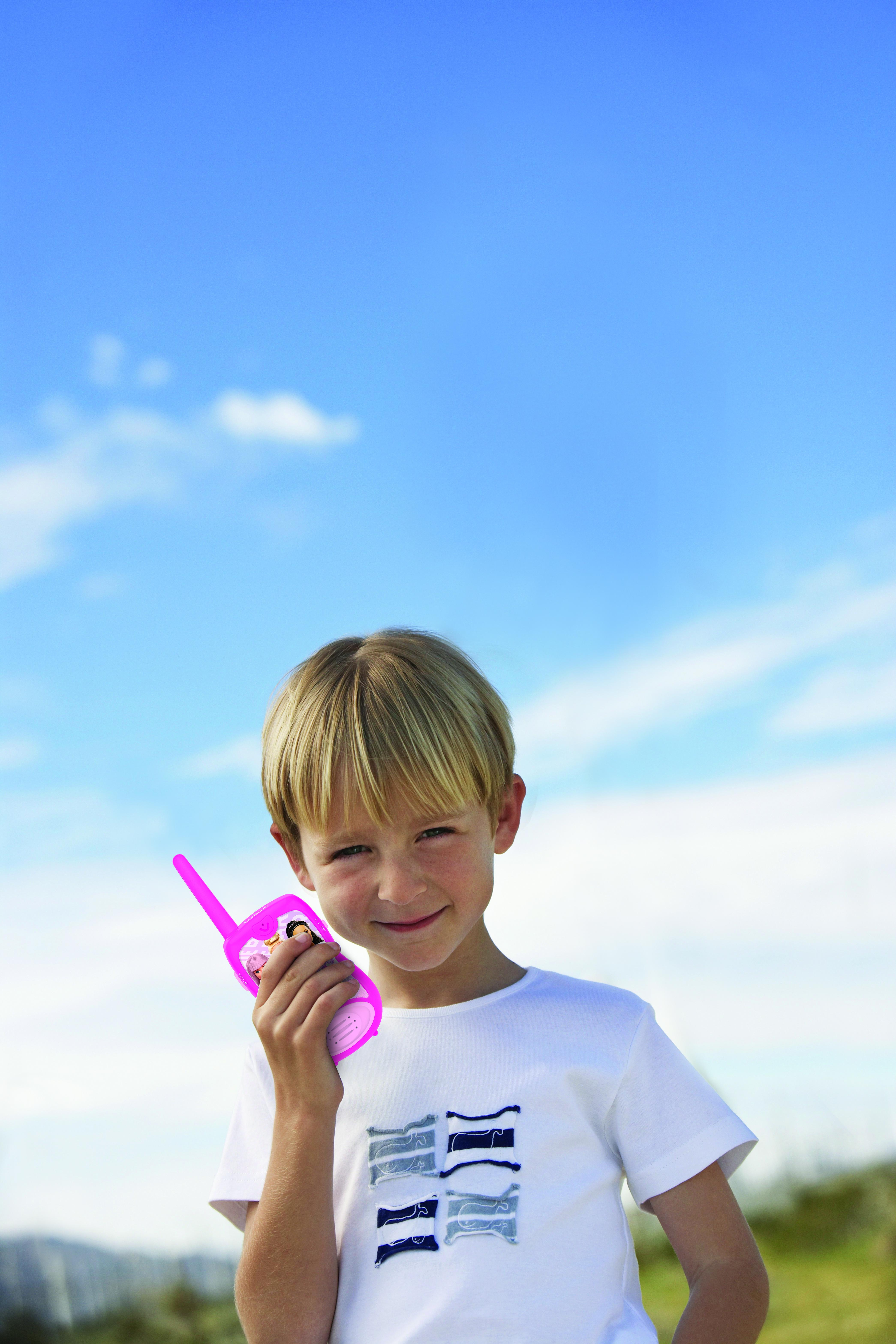 Un ragazzo tiene un walkie-talkie rosa contro un cielo blu.
