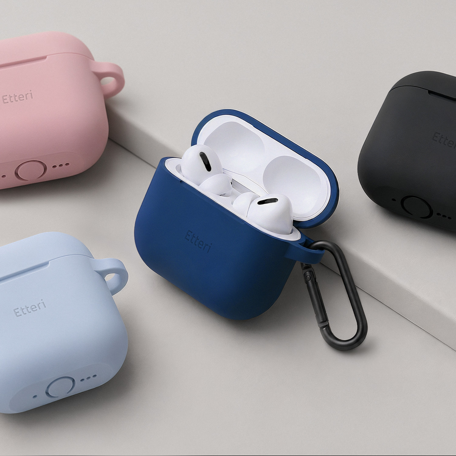 Quattro custodie in silicone per auricolari: rosa, blu, blu navy e nero. Custodia blu navy aperta con auricolari.