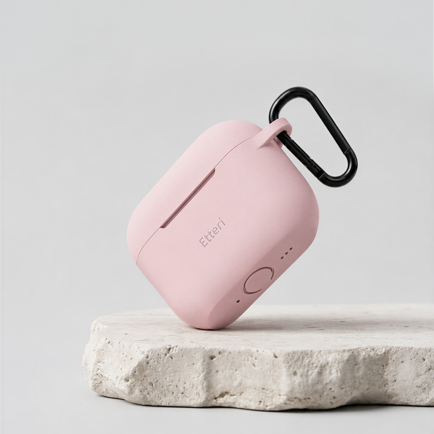 Una custodia rosa per auricolari con moschettone nero su una pietra.