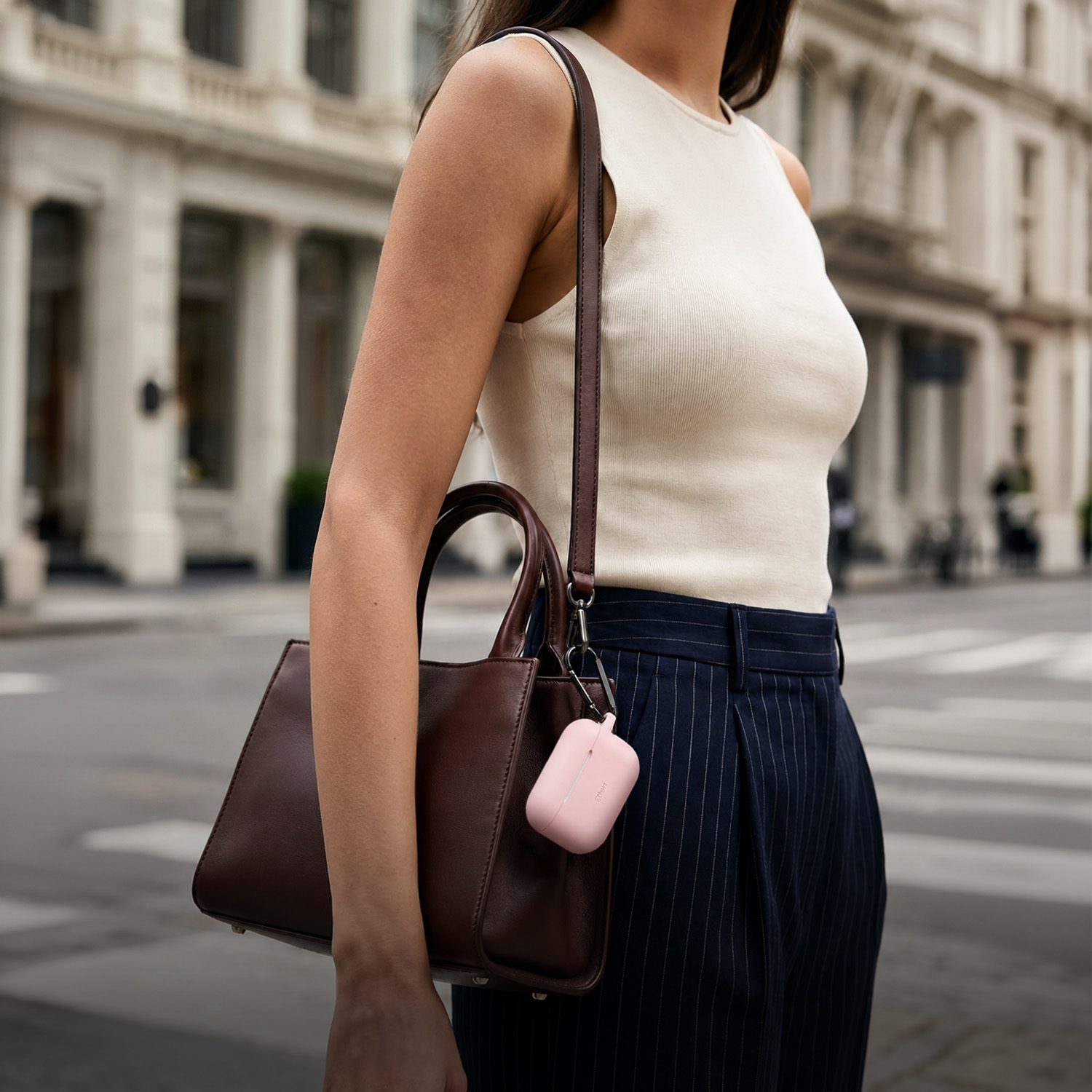 Donna con borsa marrone scuro e custodia rosa, in contesto urbano.