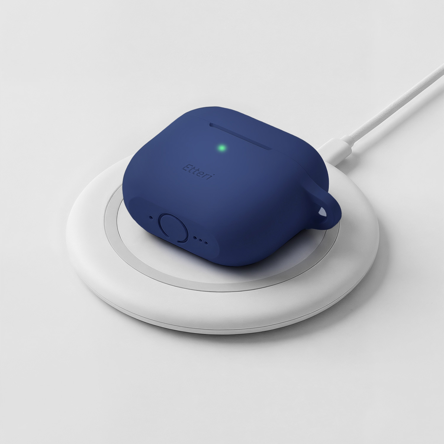 Una custodia di ricarica blu scuro per auricolari si ricarica wireless su una base di ricarica bianca.