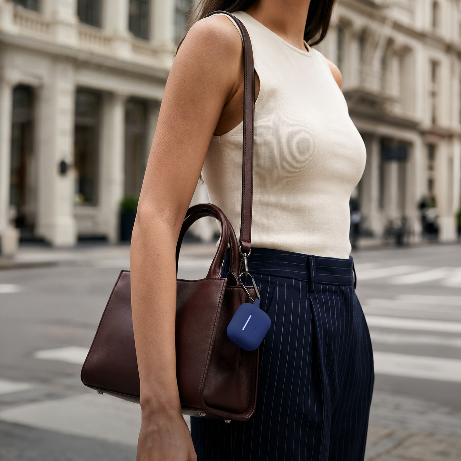 Donna con borsa e custodia blu per auricolari, sfondo di strada urbana.