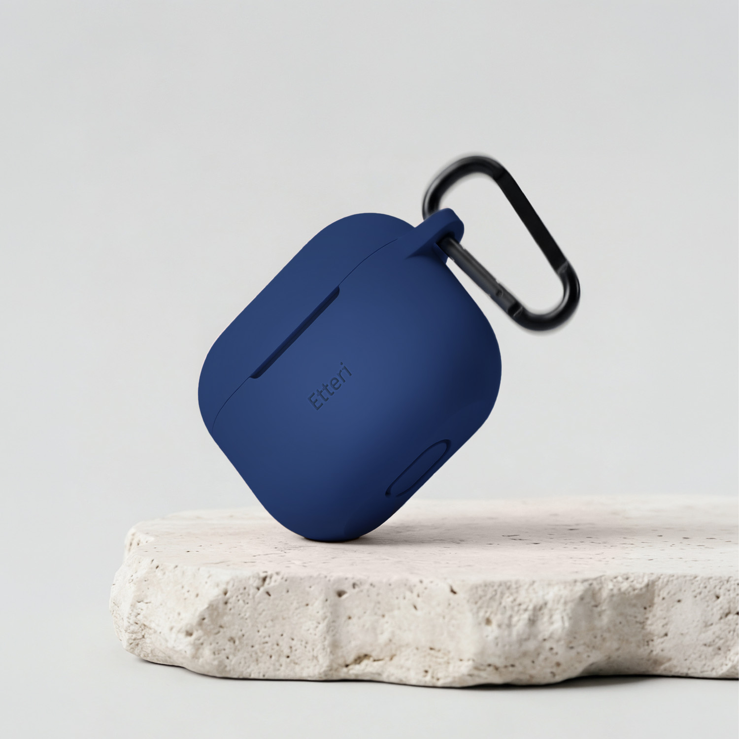 Custodia blu scuro con moschettone su piedistallo di pietra.