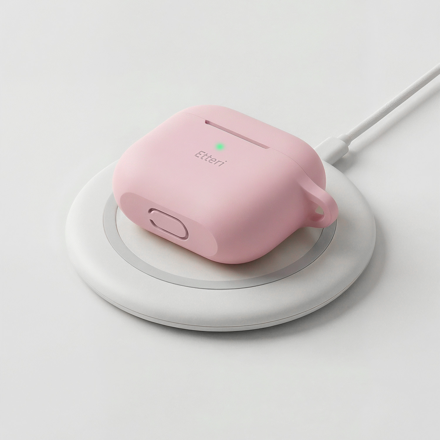 Una custodia rosa per auricolari wireless poggia su un pad di ricarica bianco.