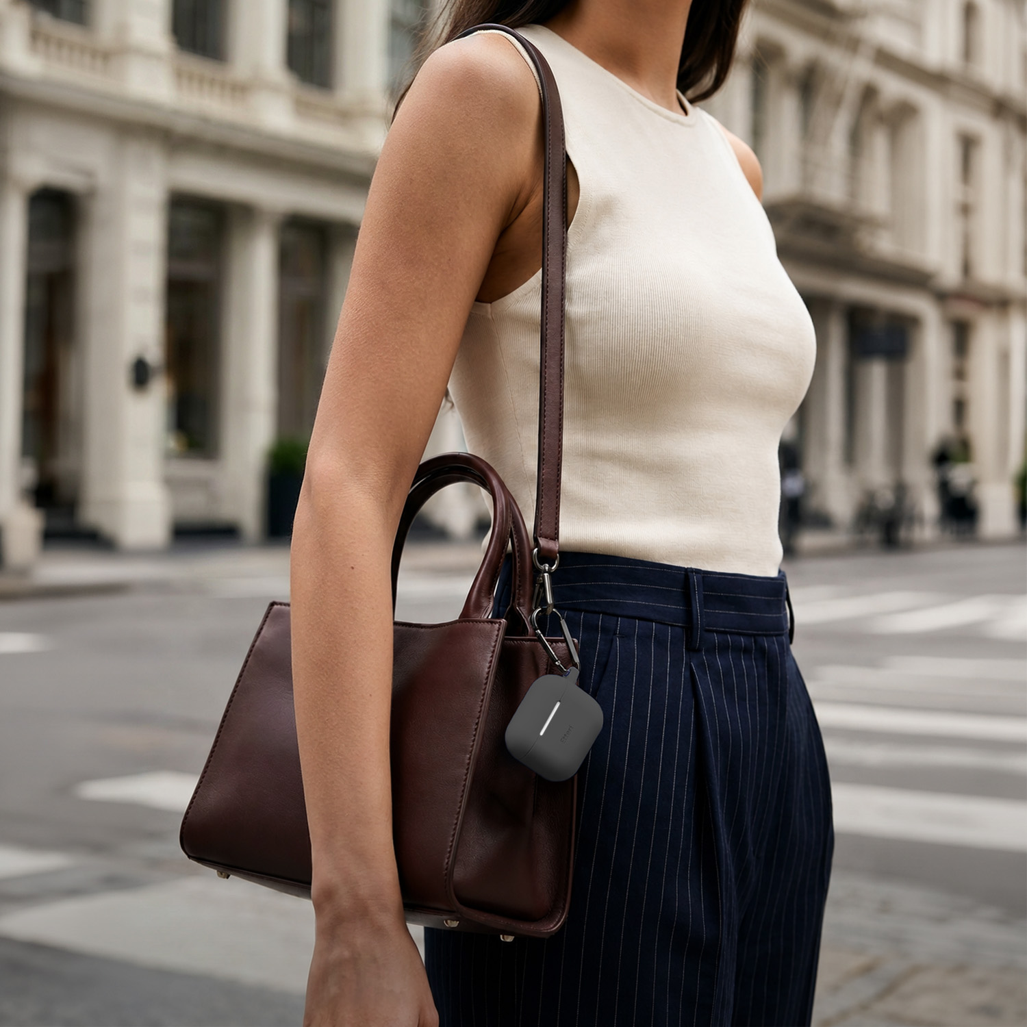 Donna con borsa marrone e custodia grigia per auricolari.