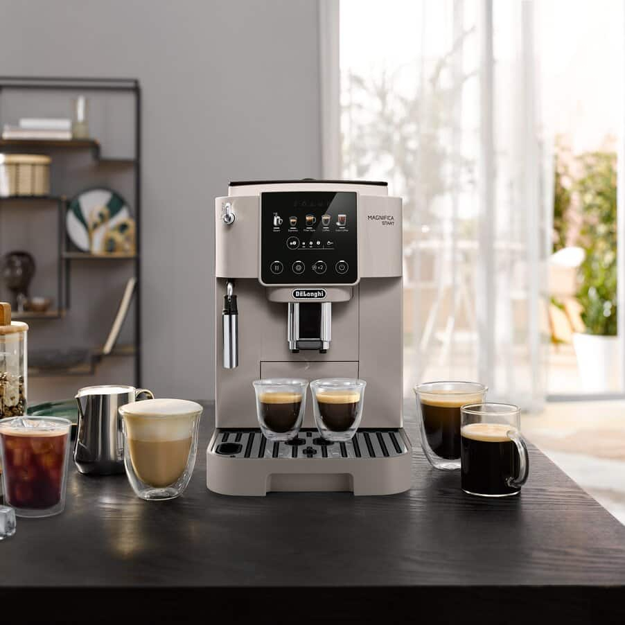 Yanında dört fincan kahve bulunan bej rengi DeLonghi kahve makinesi.