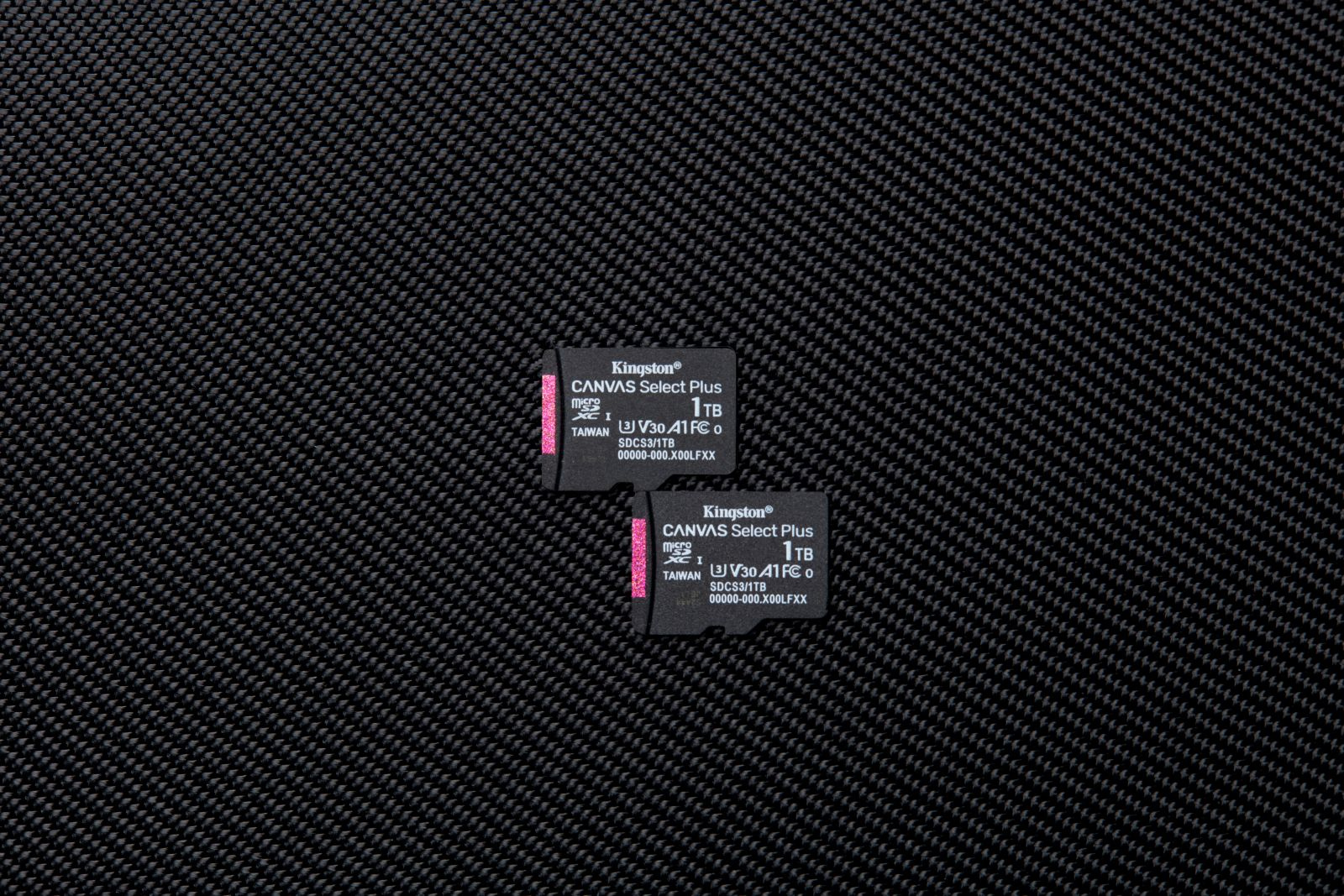 Zwei Kingston 1TB microSD-Karten auf einer texturierten schwarzen Oberfläche.