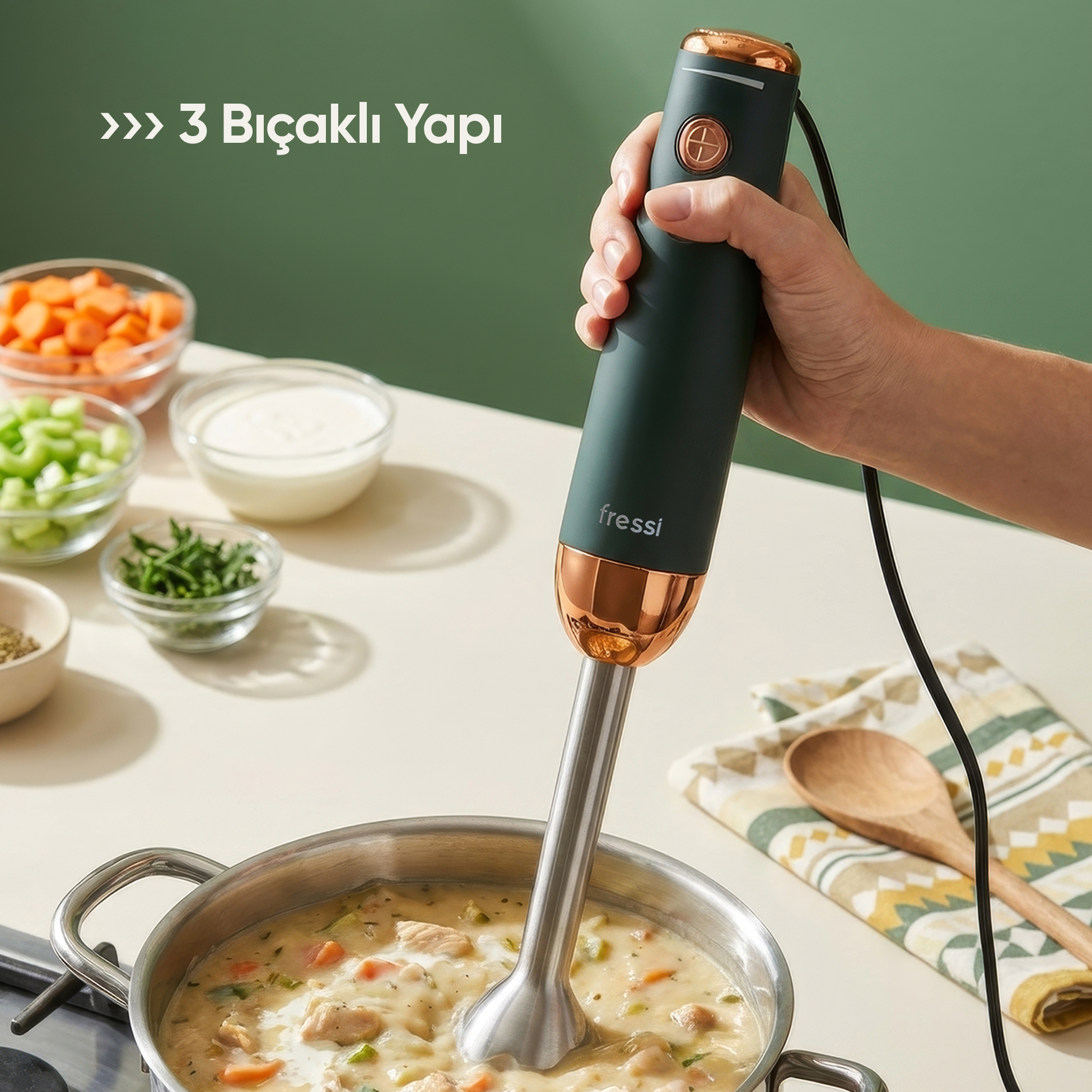 El, krema kıvamında sebzeli çorbanın olduğu tencerenin üzerinde bakır detaylı koyu blender tutuyor.