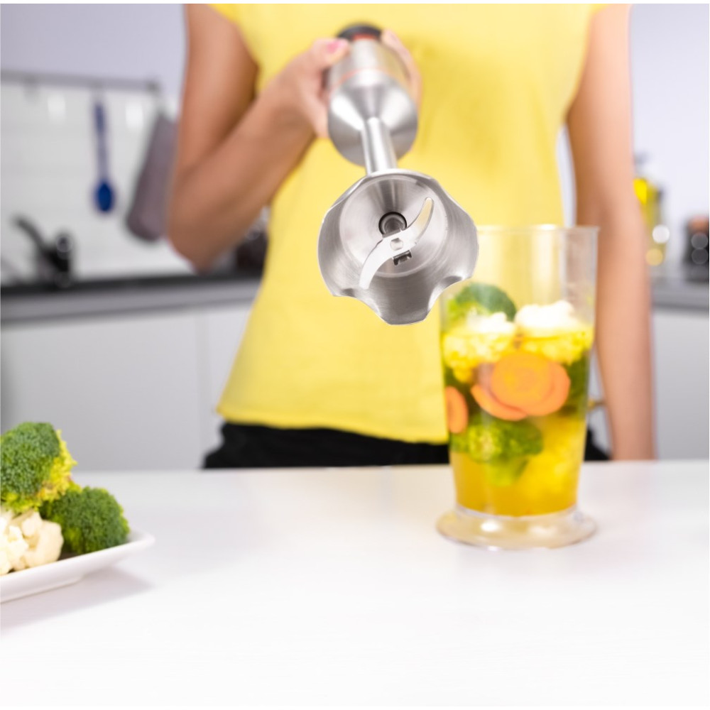 Una persona frulla broccoli, carote e cavolfiore in un contenitore di vetro.