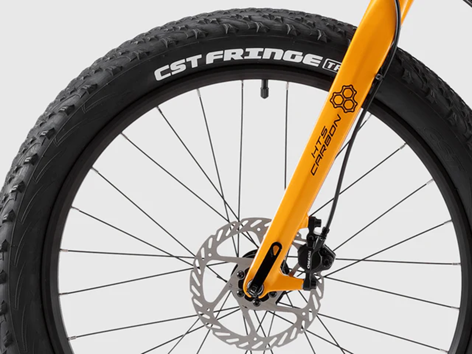 Nahaufnahme einer gelben Fahrradgabel, eines schwarzen Reifens mit CST FRINGE Schriftzug und einer Scheibenbremse.
