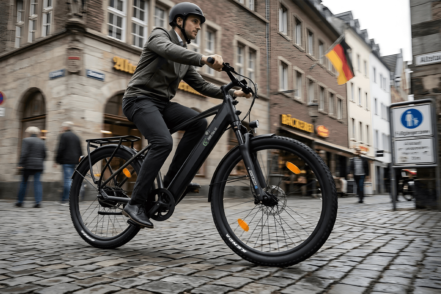 Ein Mann fährt ein schwarzes E-Bike auf einer Kopfsteinpflasterstraße in einer Stadt.