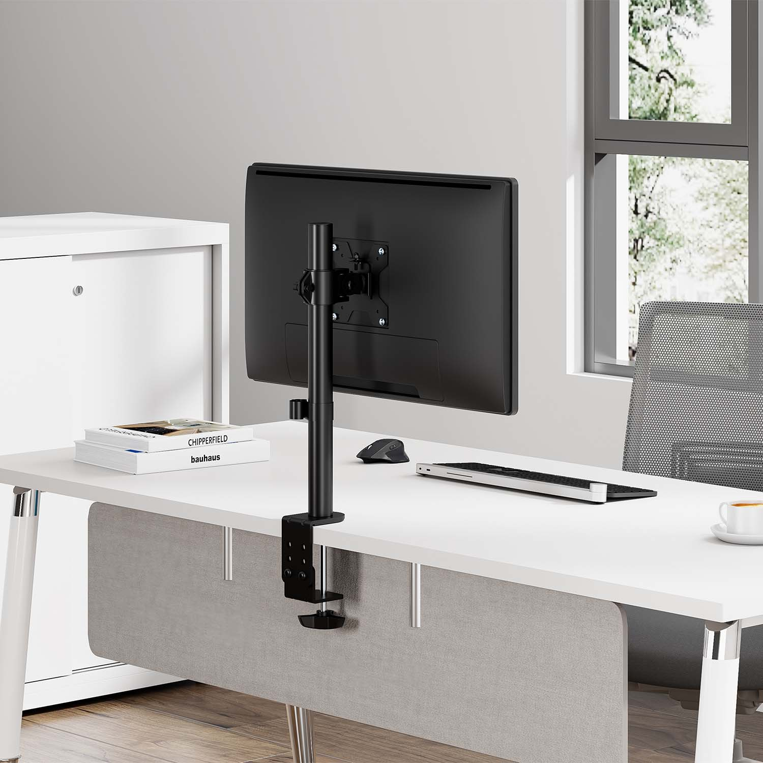 Ein Schreibtisch mit einem Monitor, Tastatur, Maus, Büchern und einer Kaffeetasse.