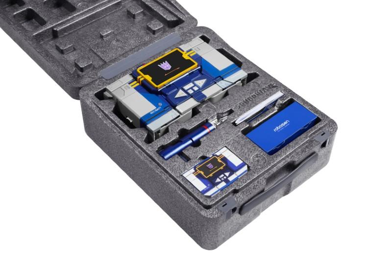 Un robot de juguete estilo radiocasete yace en una caja de espuma gris.