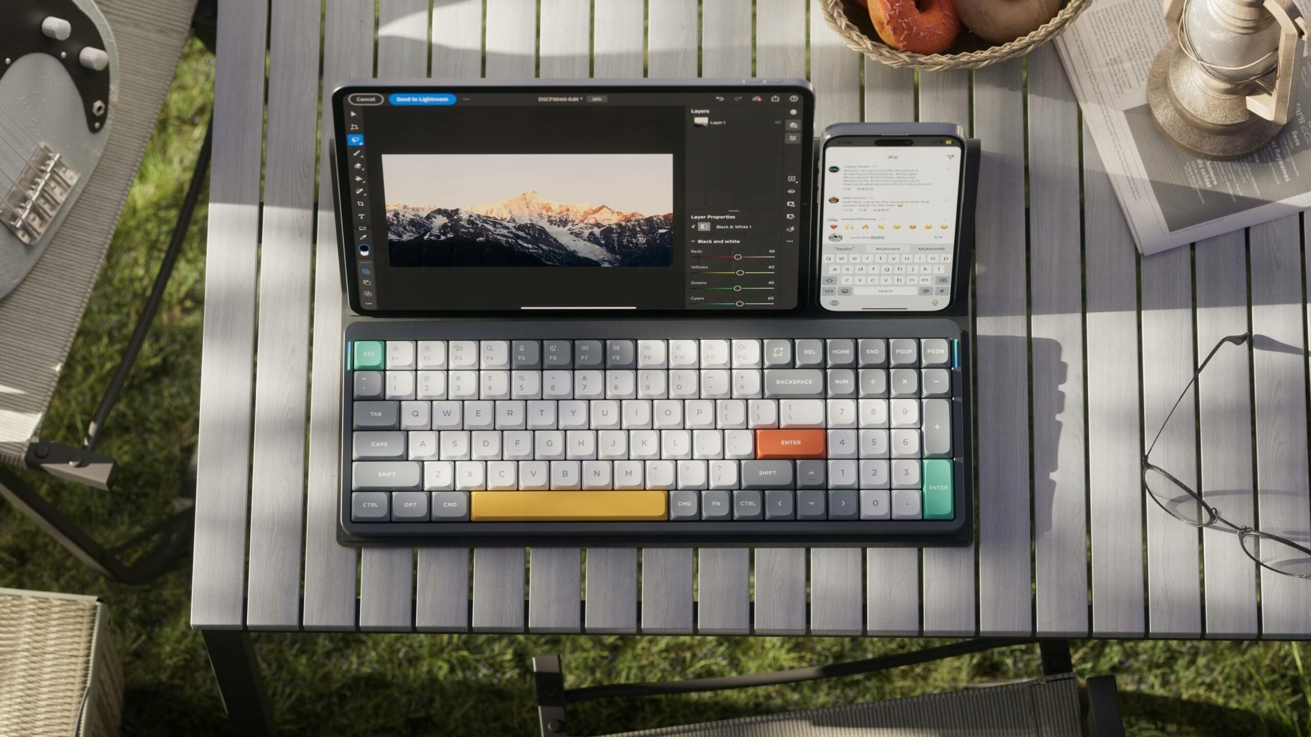 Laptop, smartfon i gitara leżą na drewnianym stole na zewnątrz.